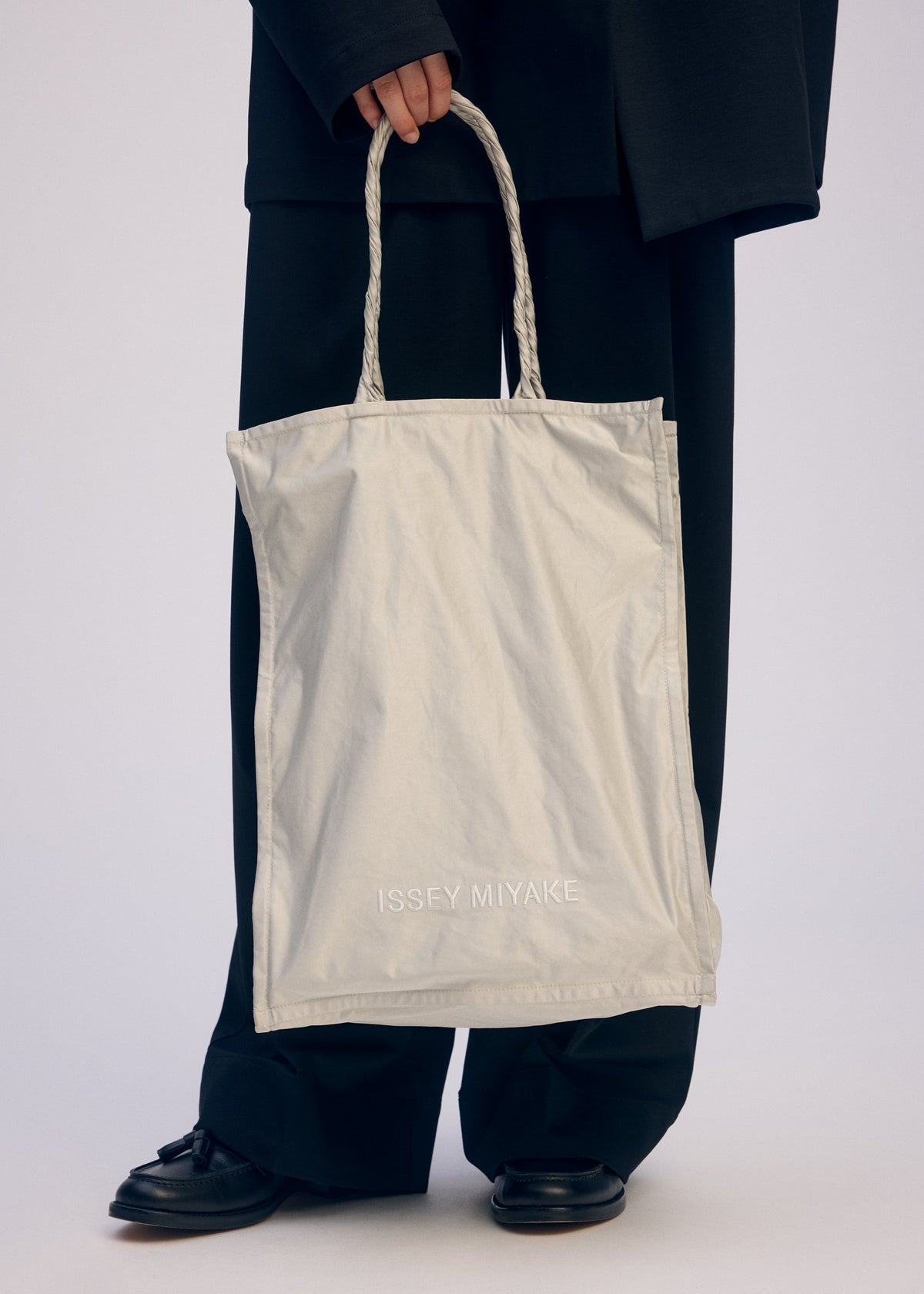 A model wears the ISSEY MIYAKE CRUMPLABLE bag.