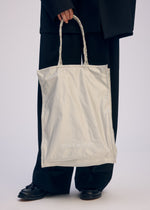 A model wears the ISSEY MIYAKE CRUMPLABLE bag.