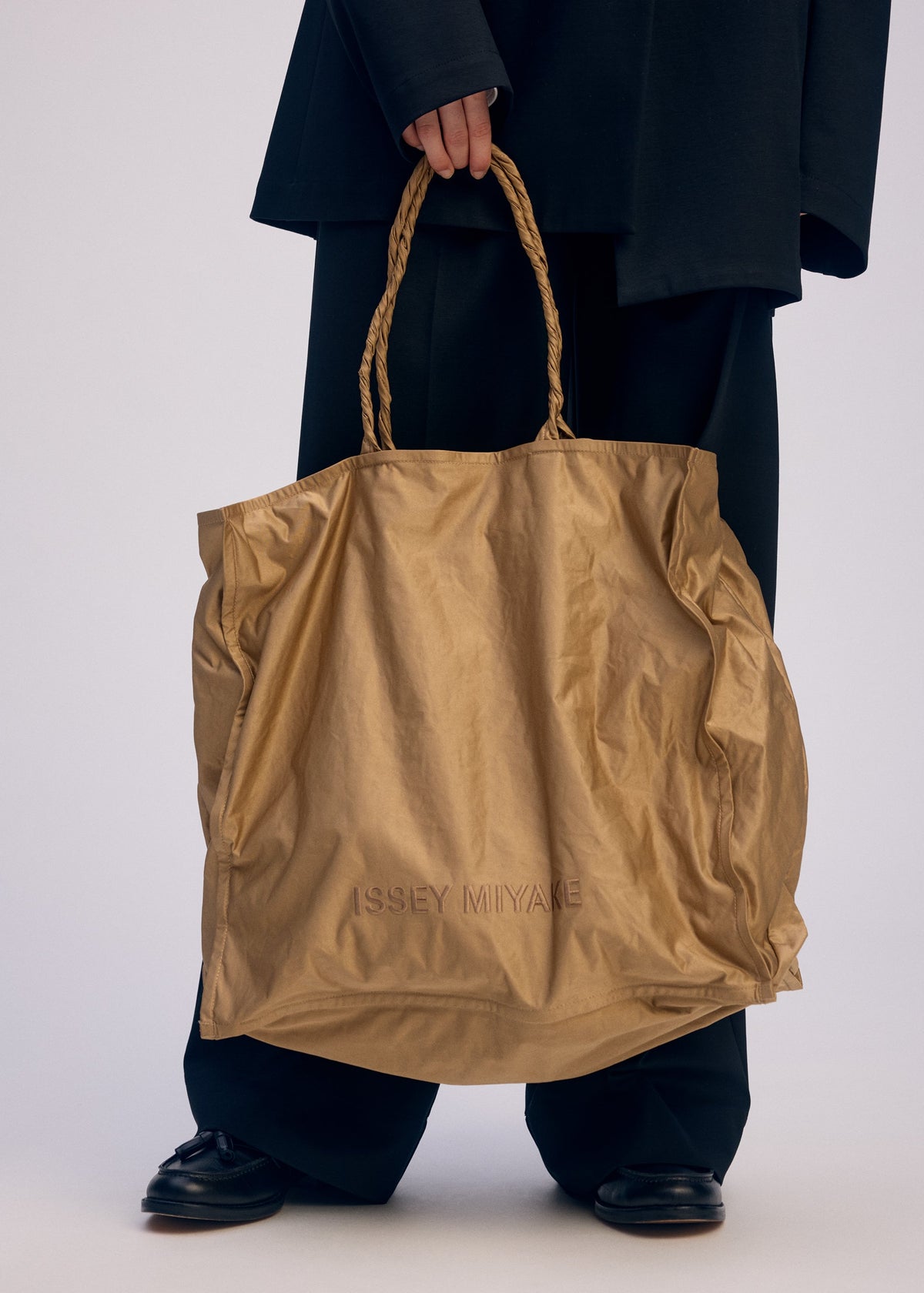 A model wears the ISSEY MIYAKE CRUMPLABLE bag.