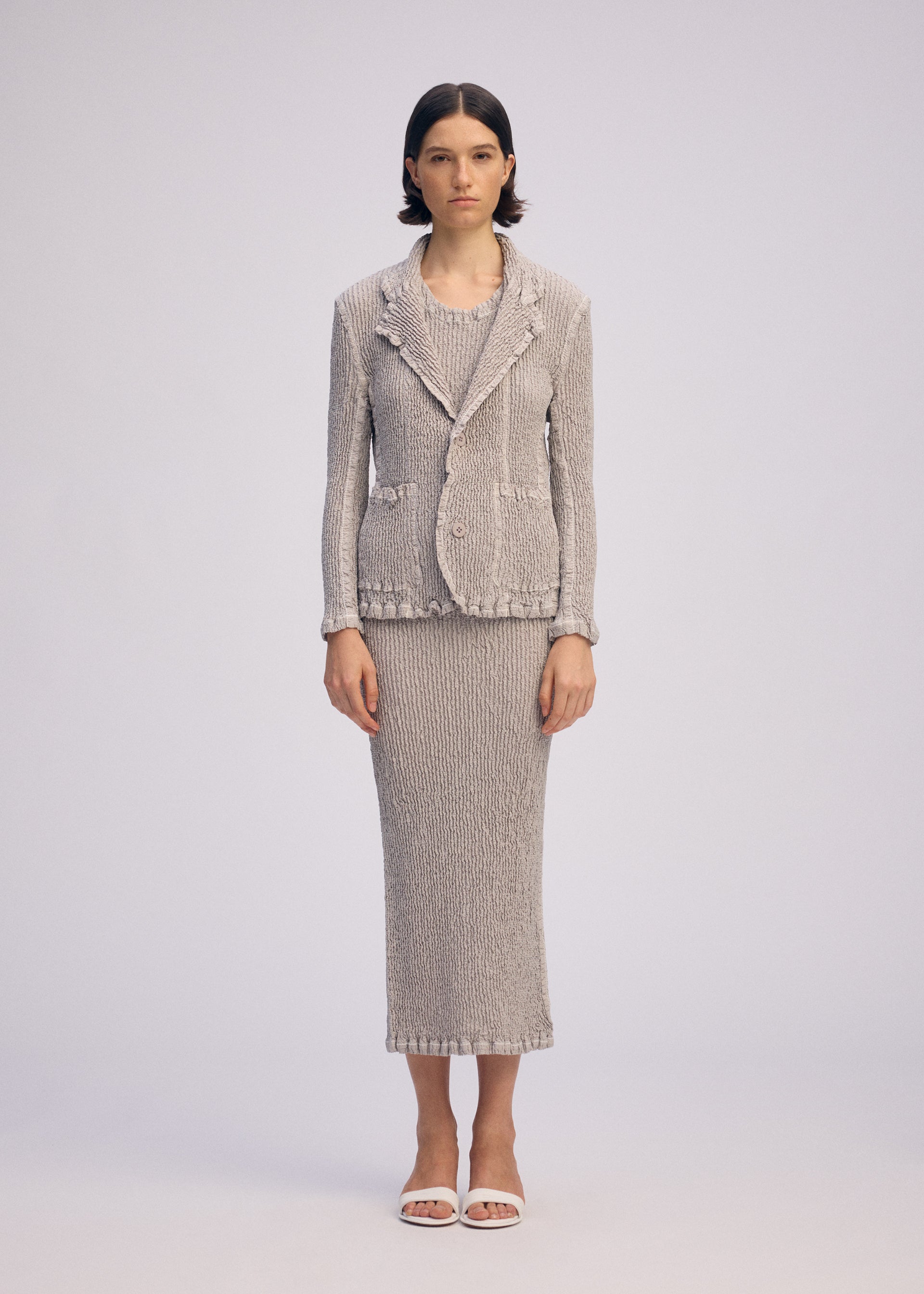 A model wears the ISSEY MIYAKE WAVELET ENSEMBLE jacket.