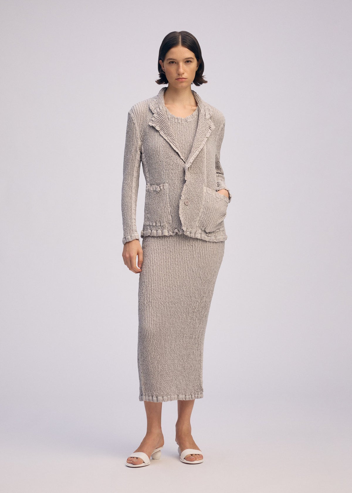 A model wears the ISSEY MIYAKE WAVELET ENSEMBLE jacket.