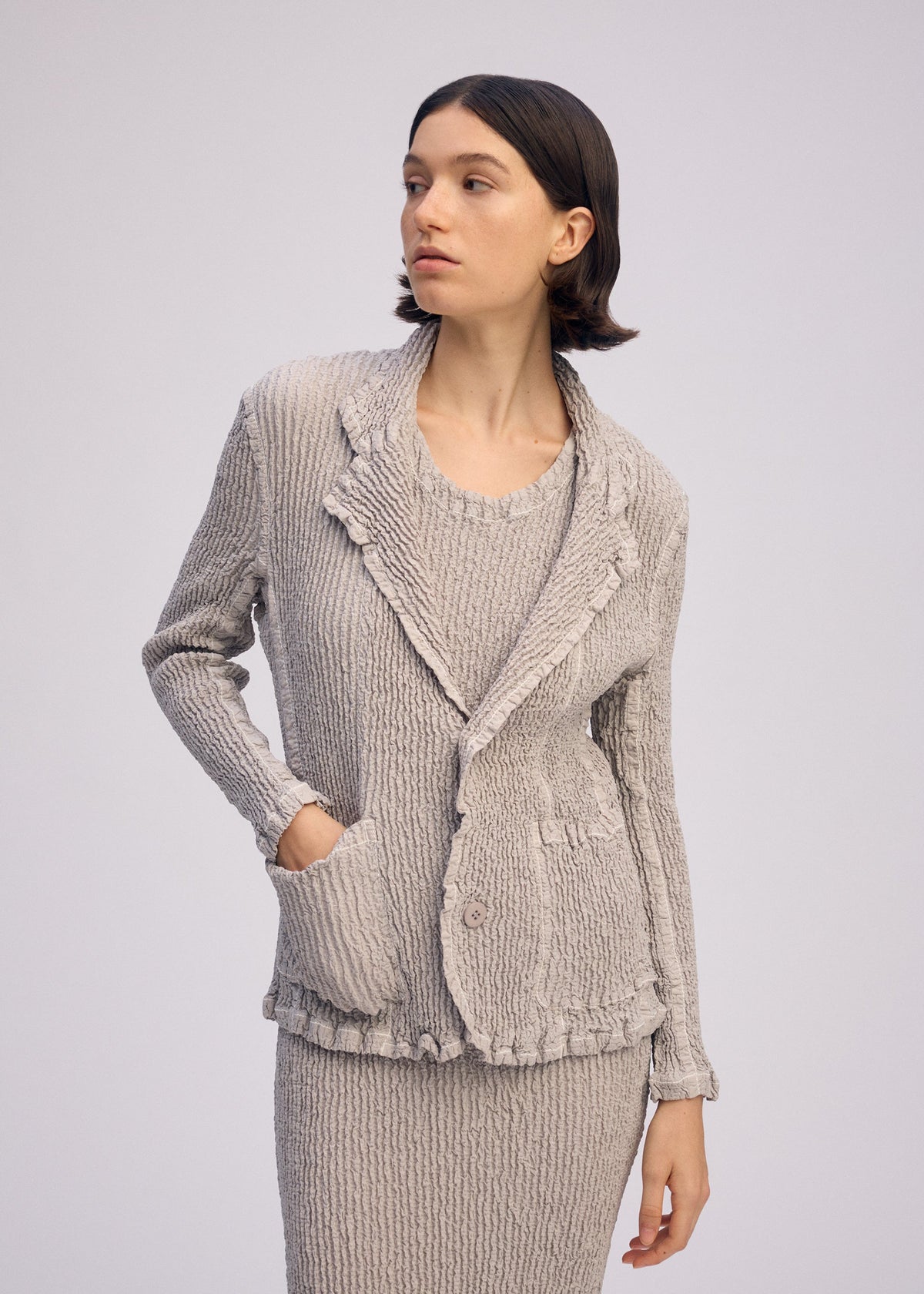 A model wears the ISSEY MIYAKE WAVELET ENSEMBLE jacket.