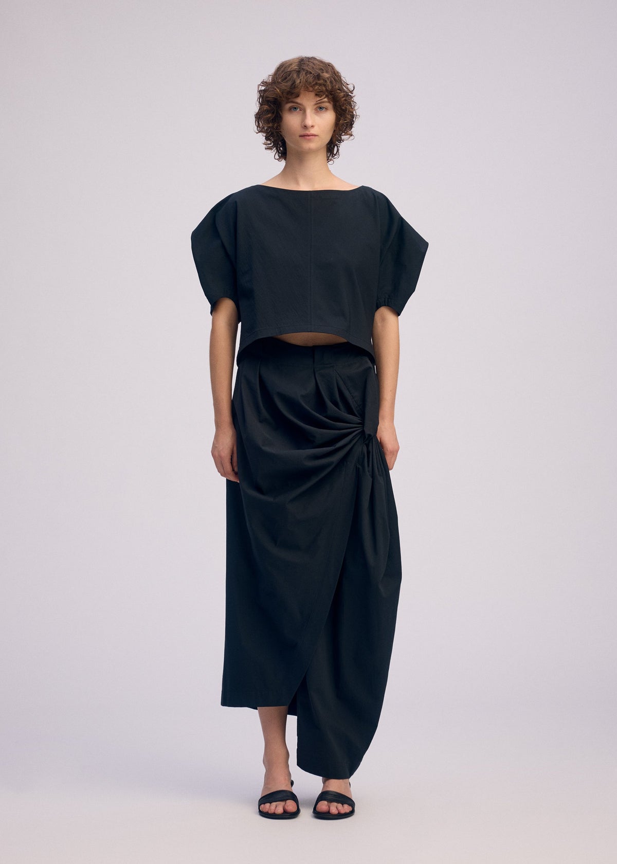 A model wears the ISSEY MIYAKE TWISTED DRAPE trousers.