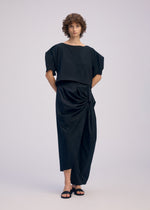 A model wears the ISSEY MIYAKE TWISTED DRAPE trousers.