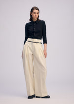 A model wears the ISSEY MIYAKE BELTED WOOL PANTS trousers.