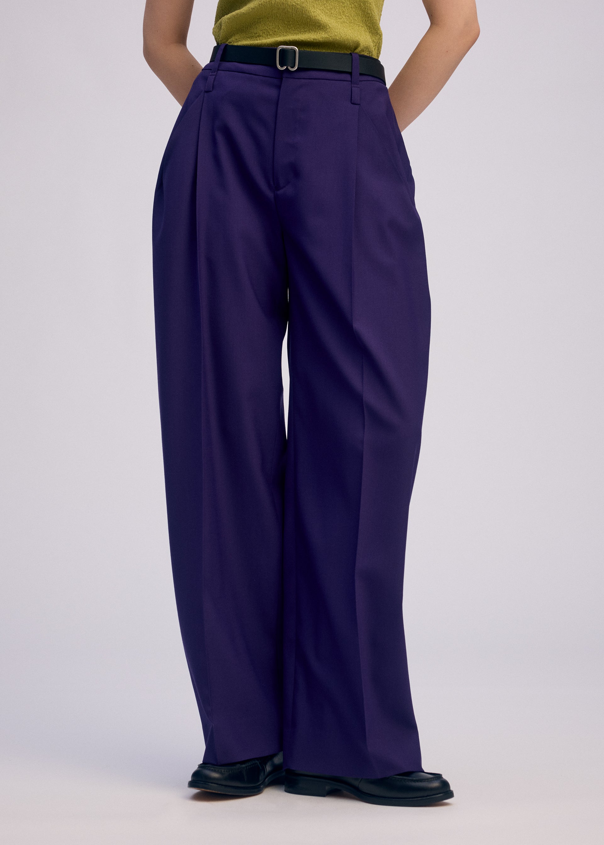 A model wears the ISSEY MIYAKE BELTED WOOL PANTS trousers.