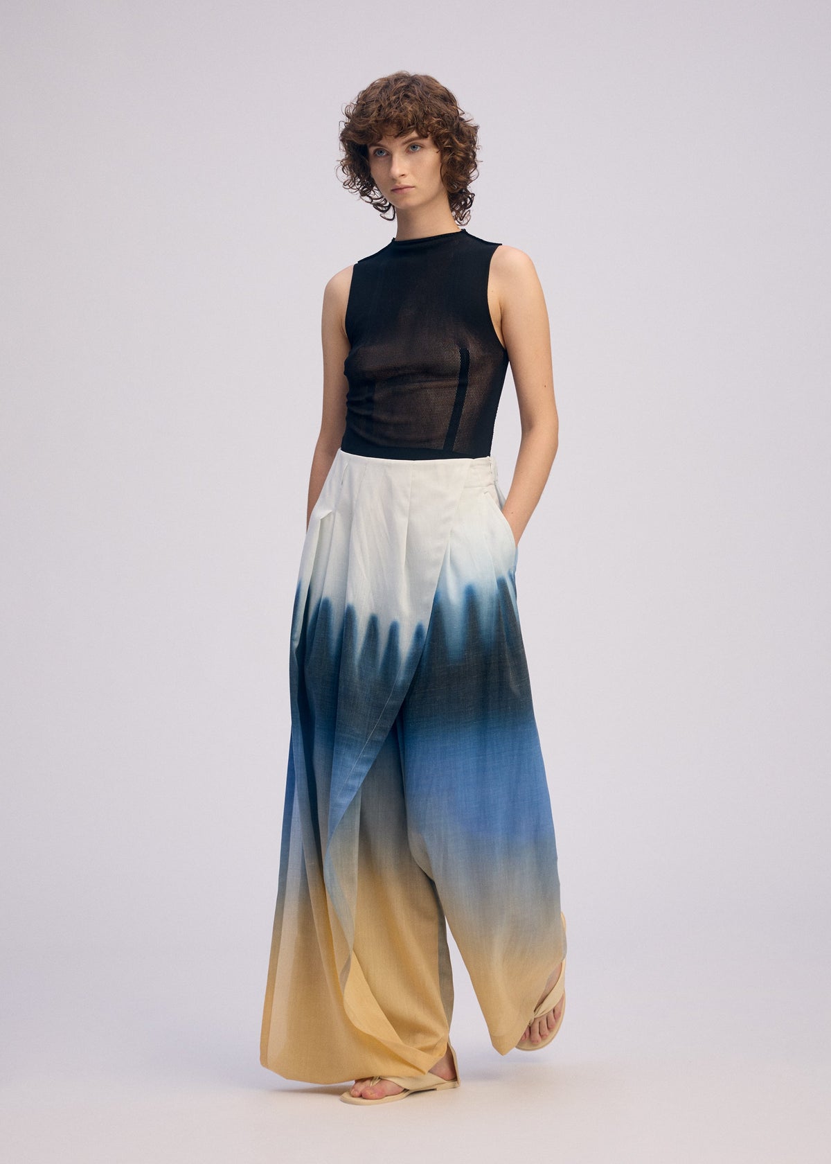 A model wears the ISSEY MIYAKE PLUMAGE plumage-trousers-starling-1.