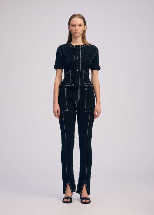 A model wears the ISSEY MIYAKE WAVELET ENSEMBLE trousers.