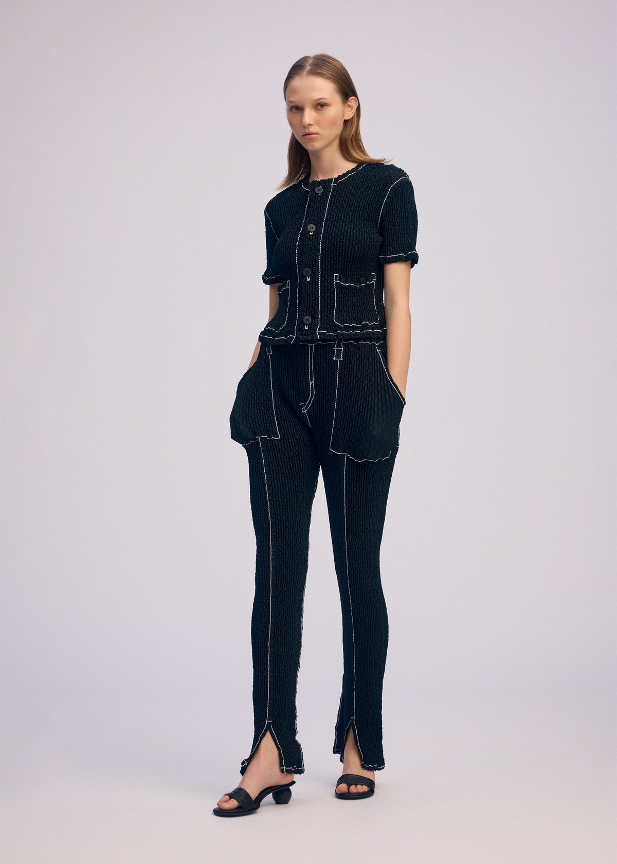 A model wears the ISSEY MIYAKE WAVELET ENSEMBLE trousers.