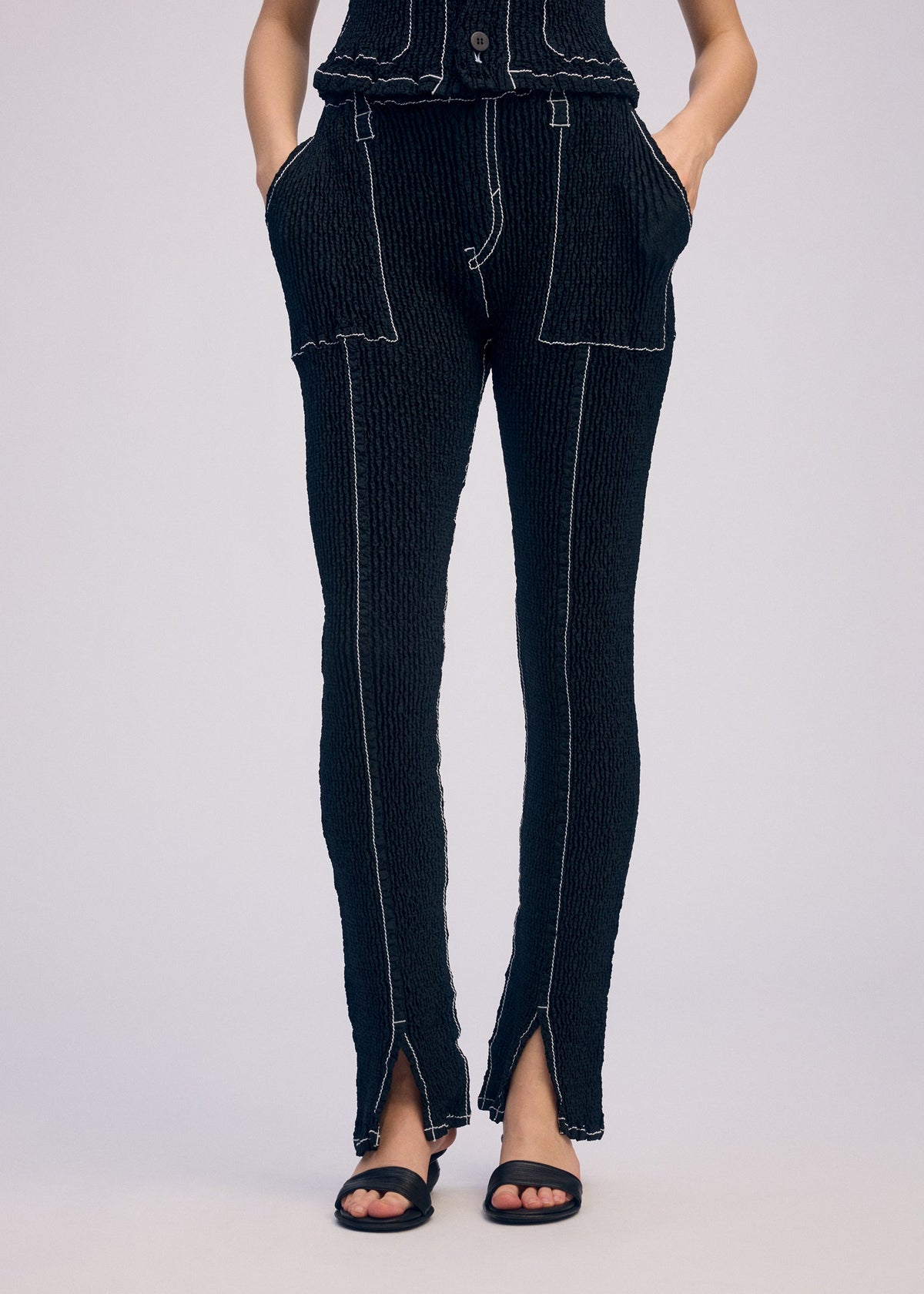 A model wears the ISSEY MIYAKE WAVELET ENSEMBLE trousers.