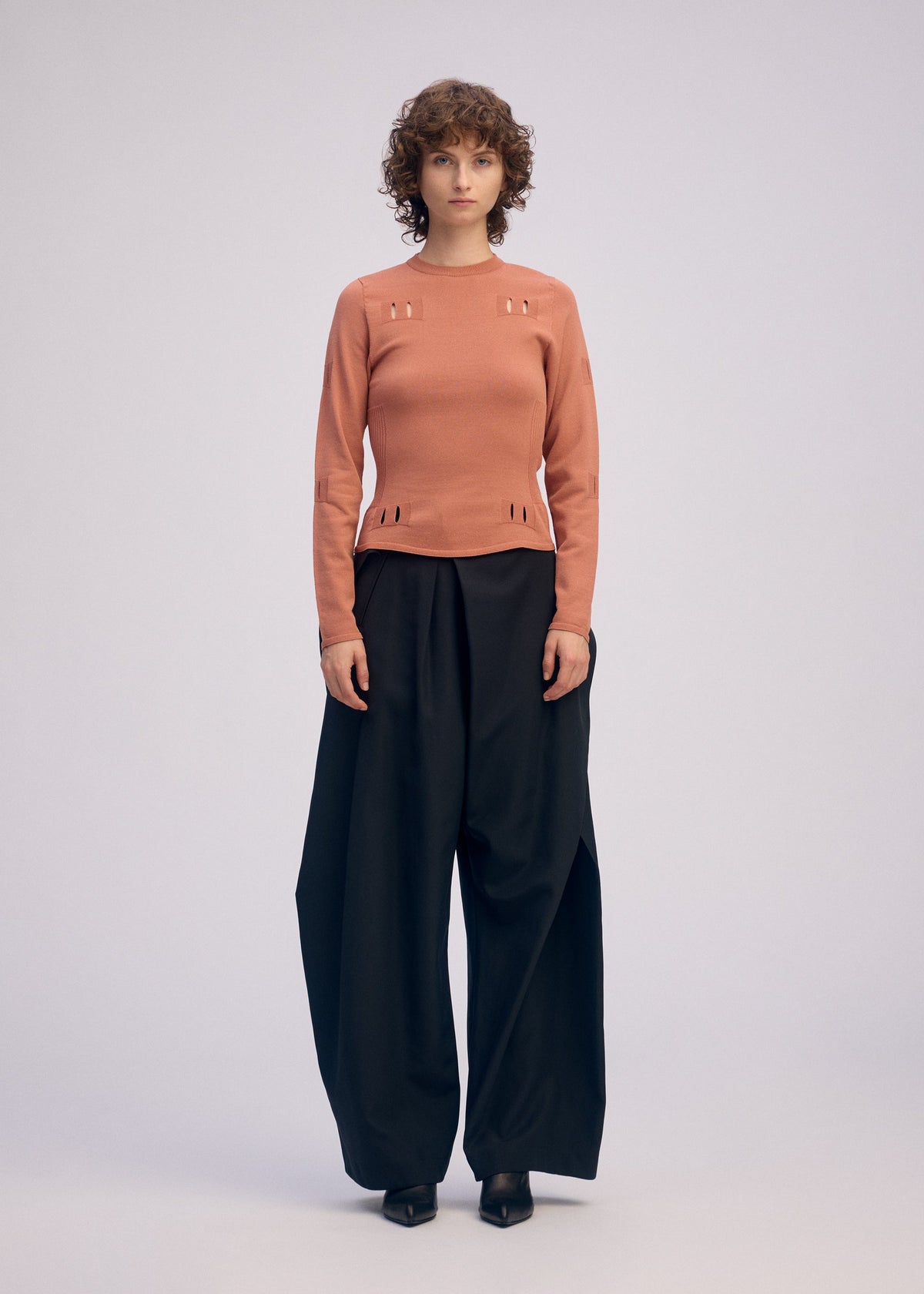 A model wears the ISSEY MIYAKE FLUTTERING PANTS trousers.