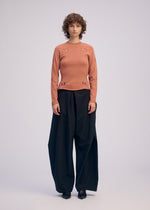 A model wears the ISSEY MIYAKE FLUTTERING PANTS trousers.