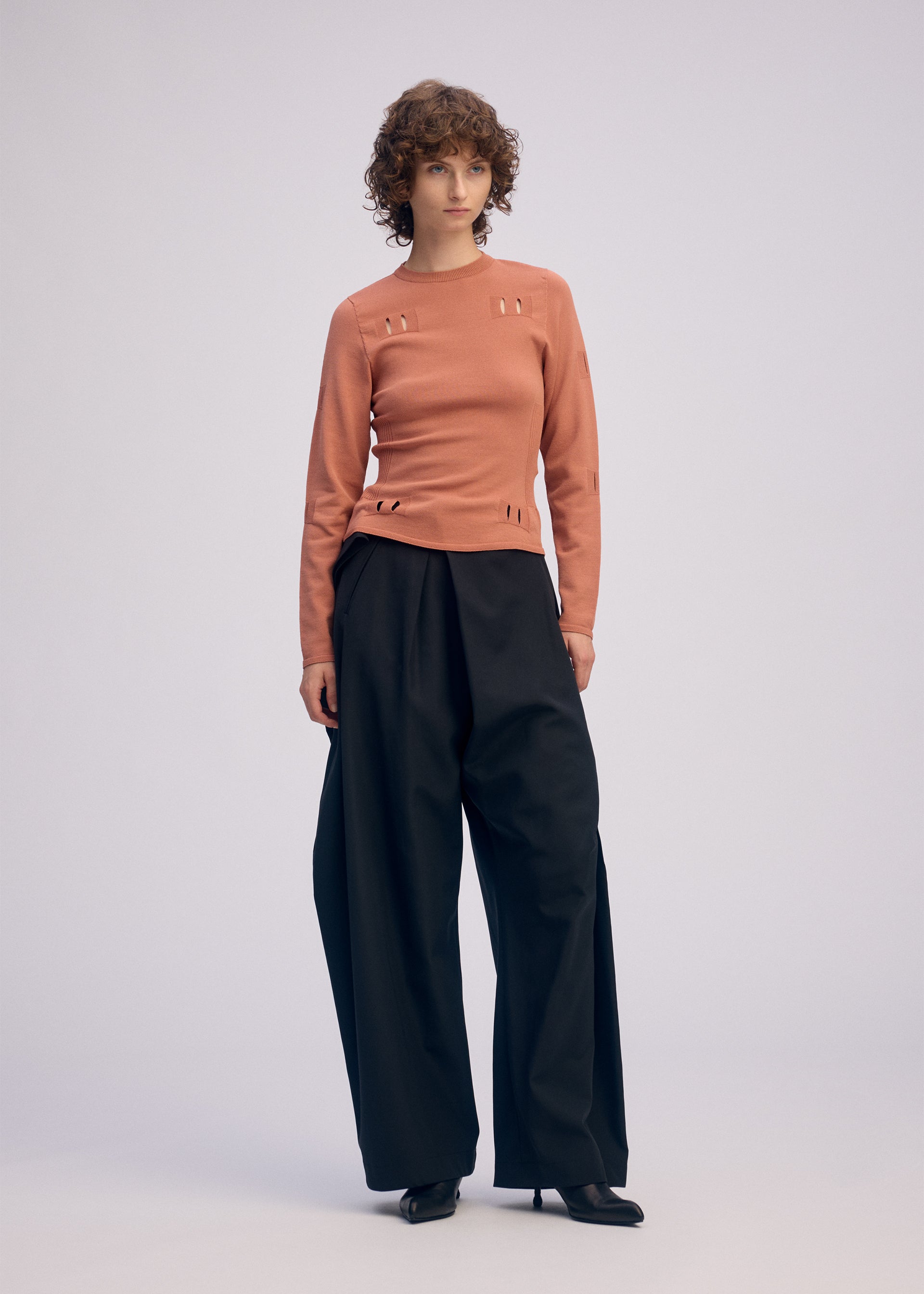 A model wears the ISSEY MIYAKE FLUTTERING PANTS trousers.