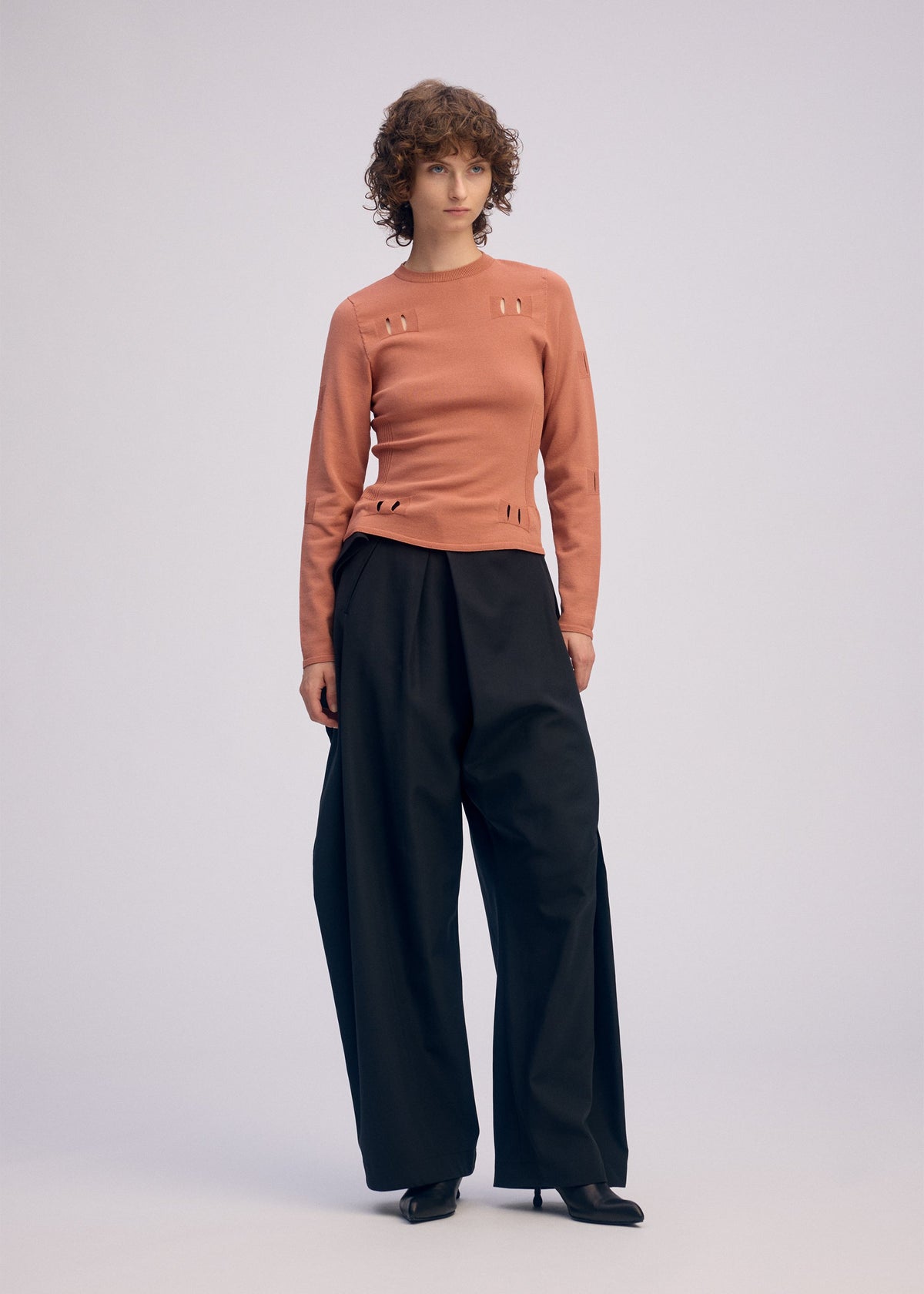 A model wears the ISSEY MIYAKE FLUTTERING PANTS trousers.