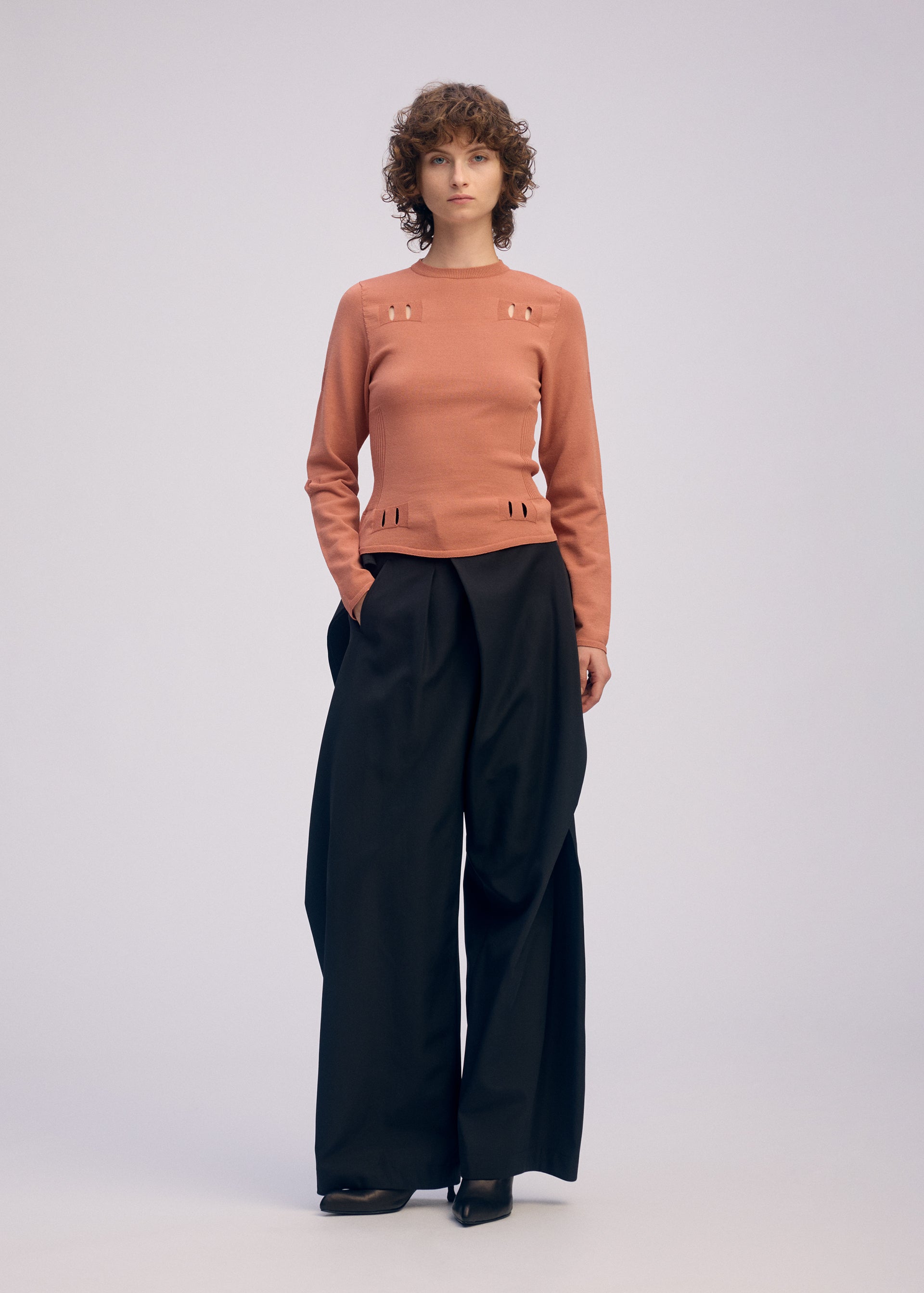A model wears the ISSEY MIYAKE FLUTTERING PANTS trousers.