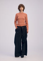 A model wears the ISSEY MIYAKE FLUTTERING PANTS trousers.
