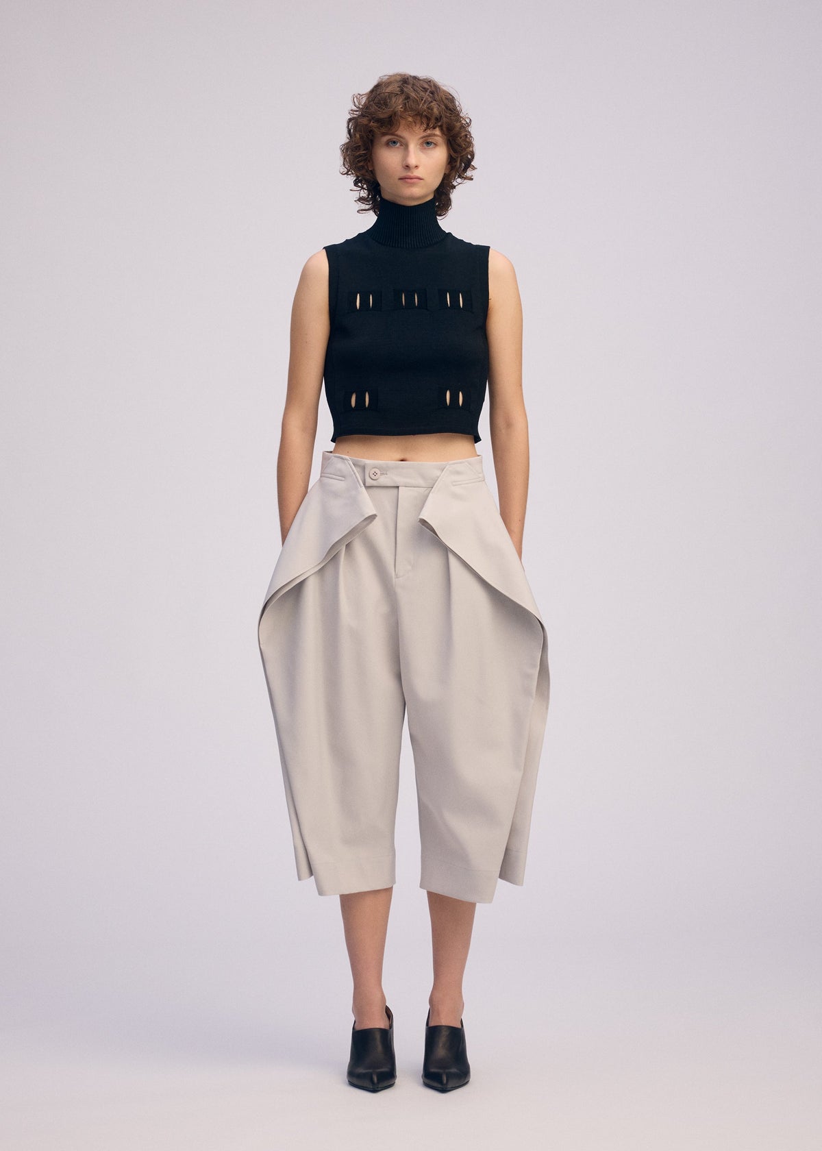 A model wears the ISSEY MIYAKE FLUTTERING PANTS trousers.
