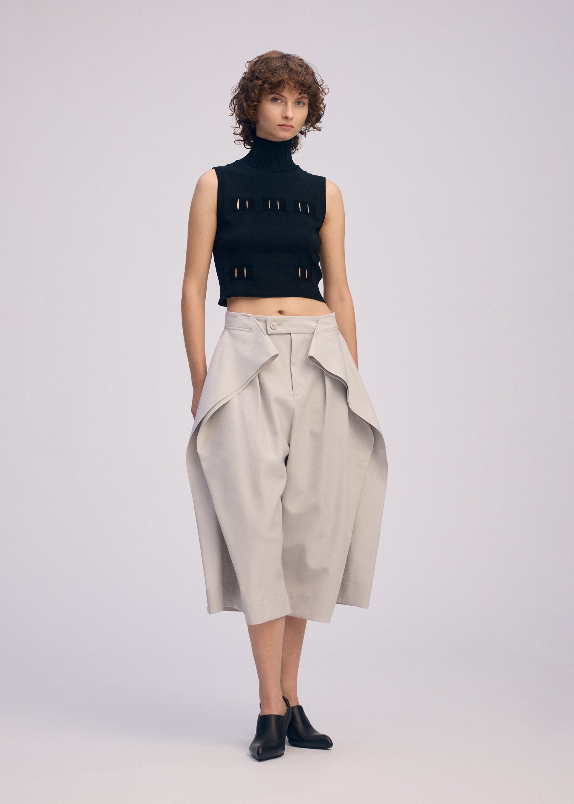 A model wears the ISSEY MIYAKE FLUTTERING PANTS trousers.