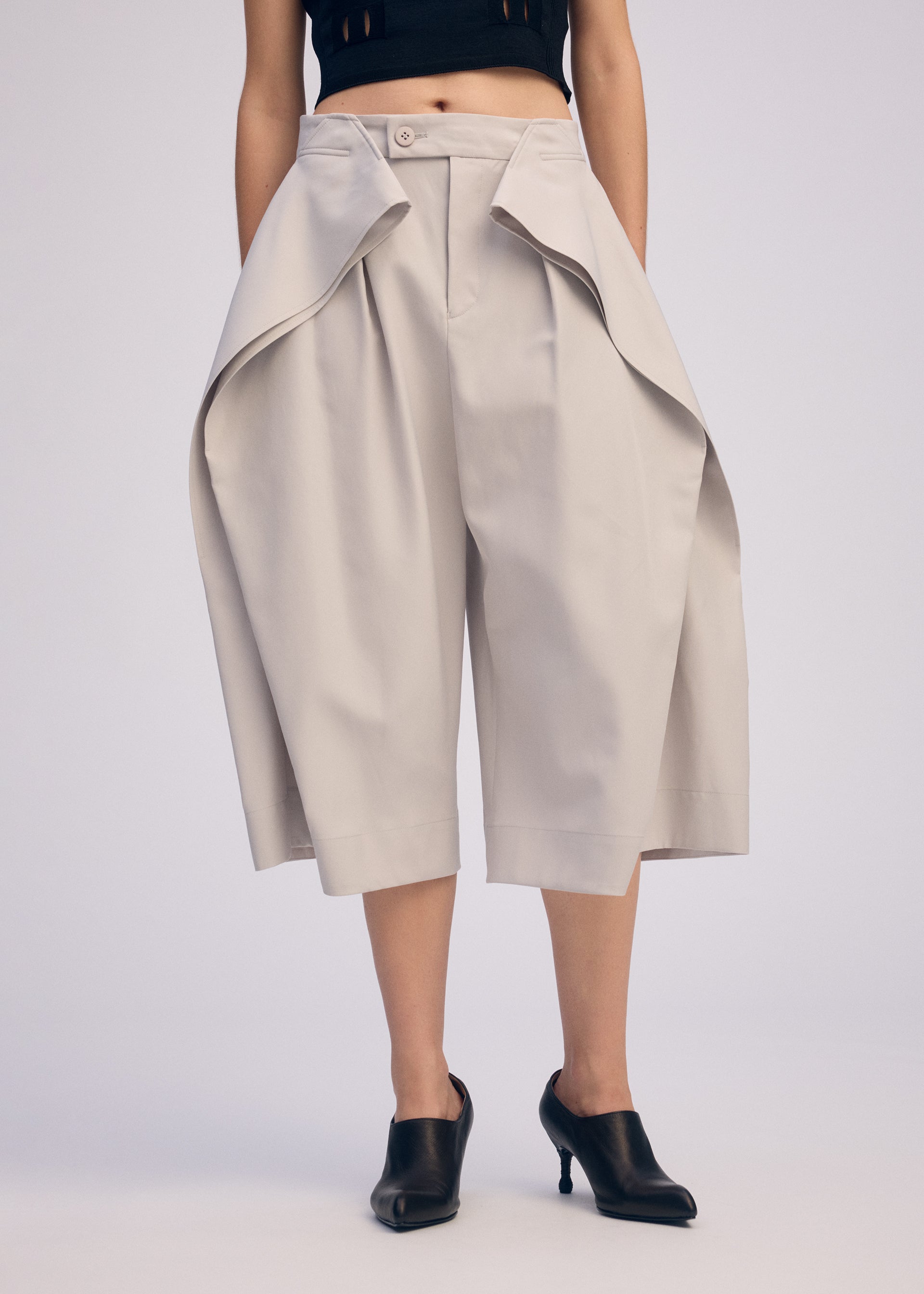 A model wears the ISSEY MIYAKE FLUTTERING PANTS trousers.