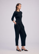 A model wears the ISSEY MIYAKE RHOMBUS PLEATS trousers.
