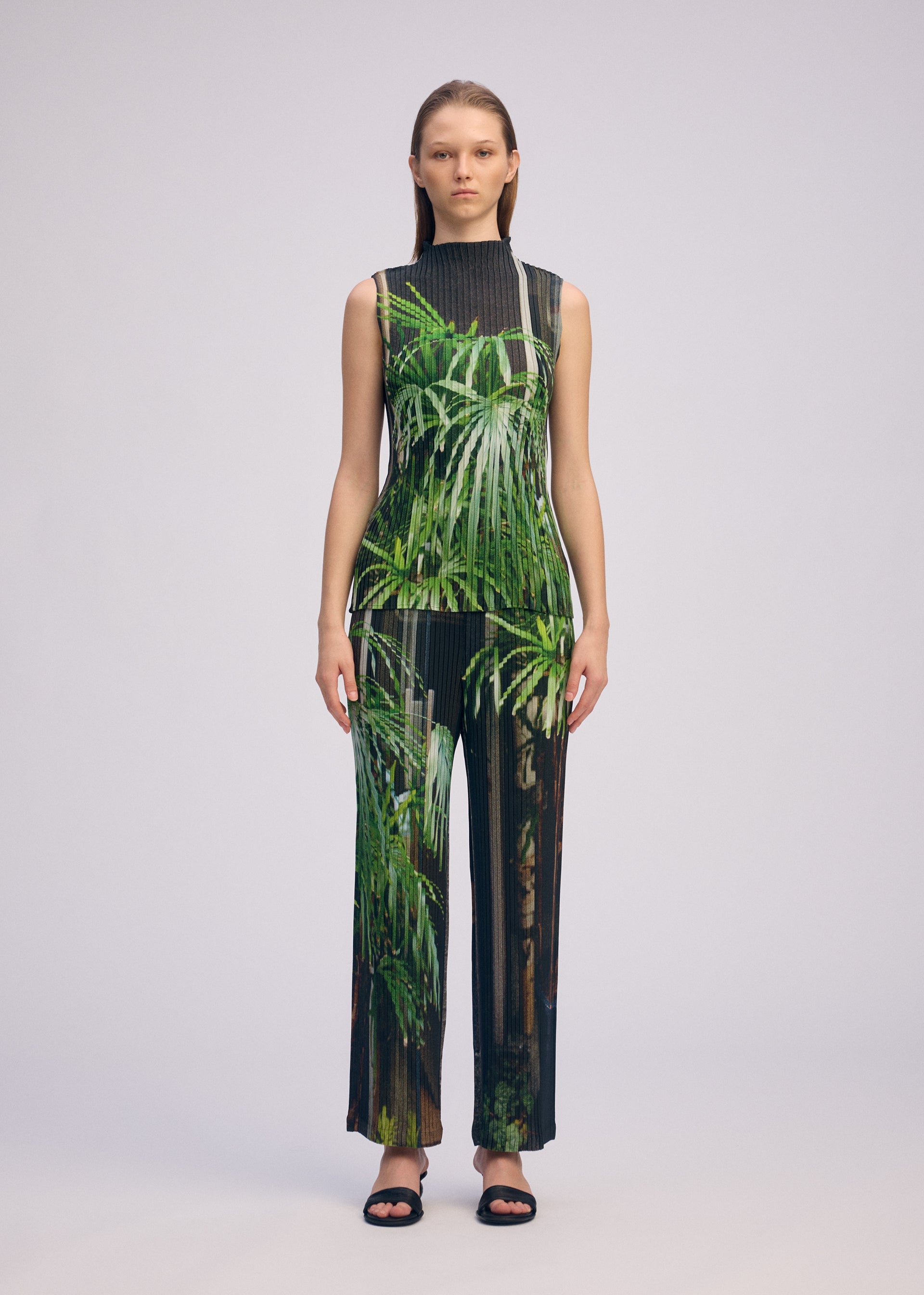A model wears the ISSEY MIYAKE URBAN JUNGLE PLEATS trousers.