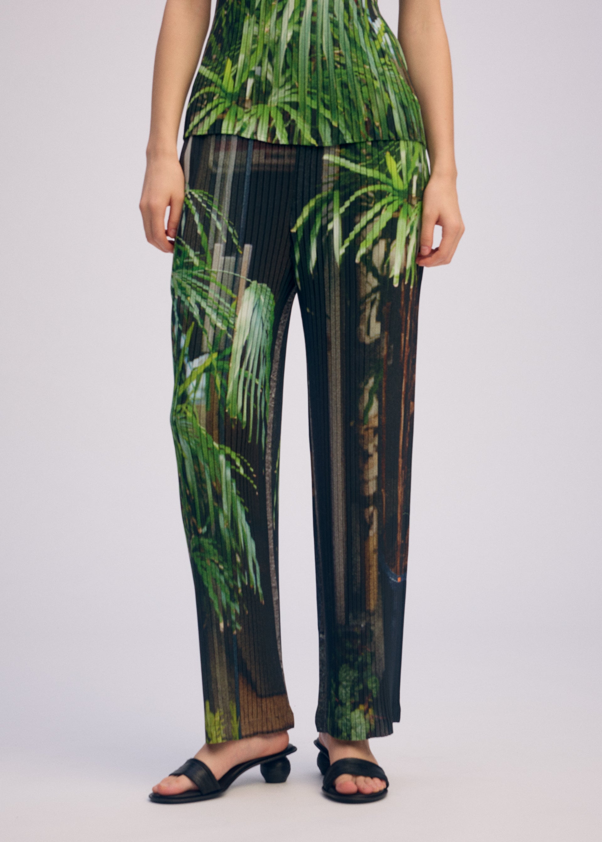 A model wears the ISSEY MIYAKE URBAN JUNGLE PLEATS trousers.