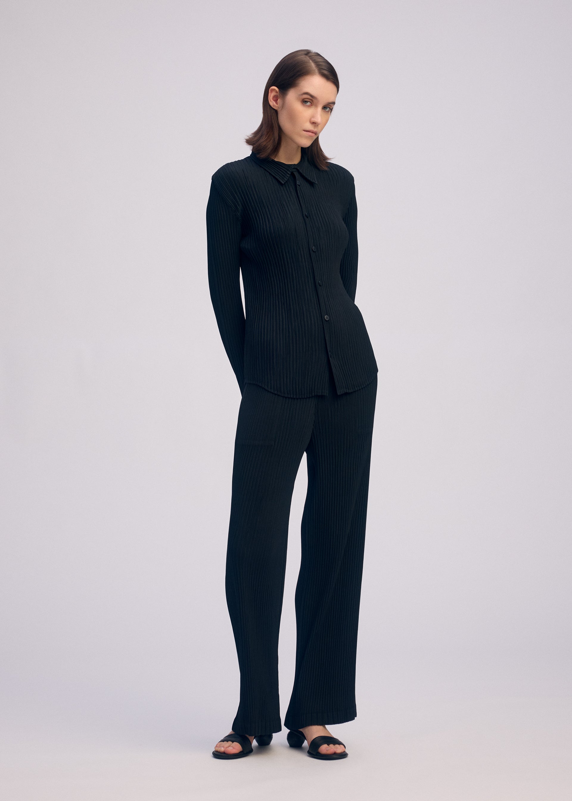A model wears the ISSEY MIYAKE HATCHING PLEATS trousers.