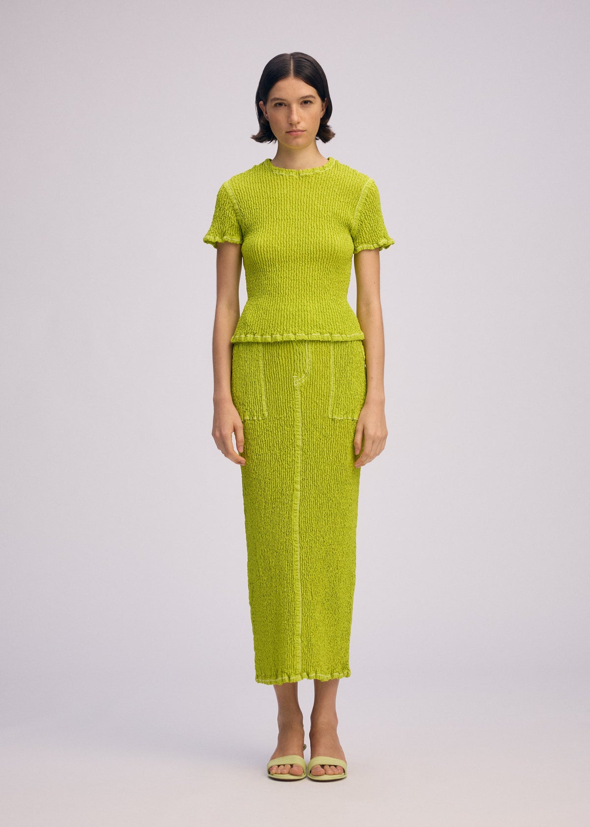 A model wears the ISSEY MIYAKE WAVELET ENSEMBLE skirt.