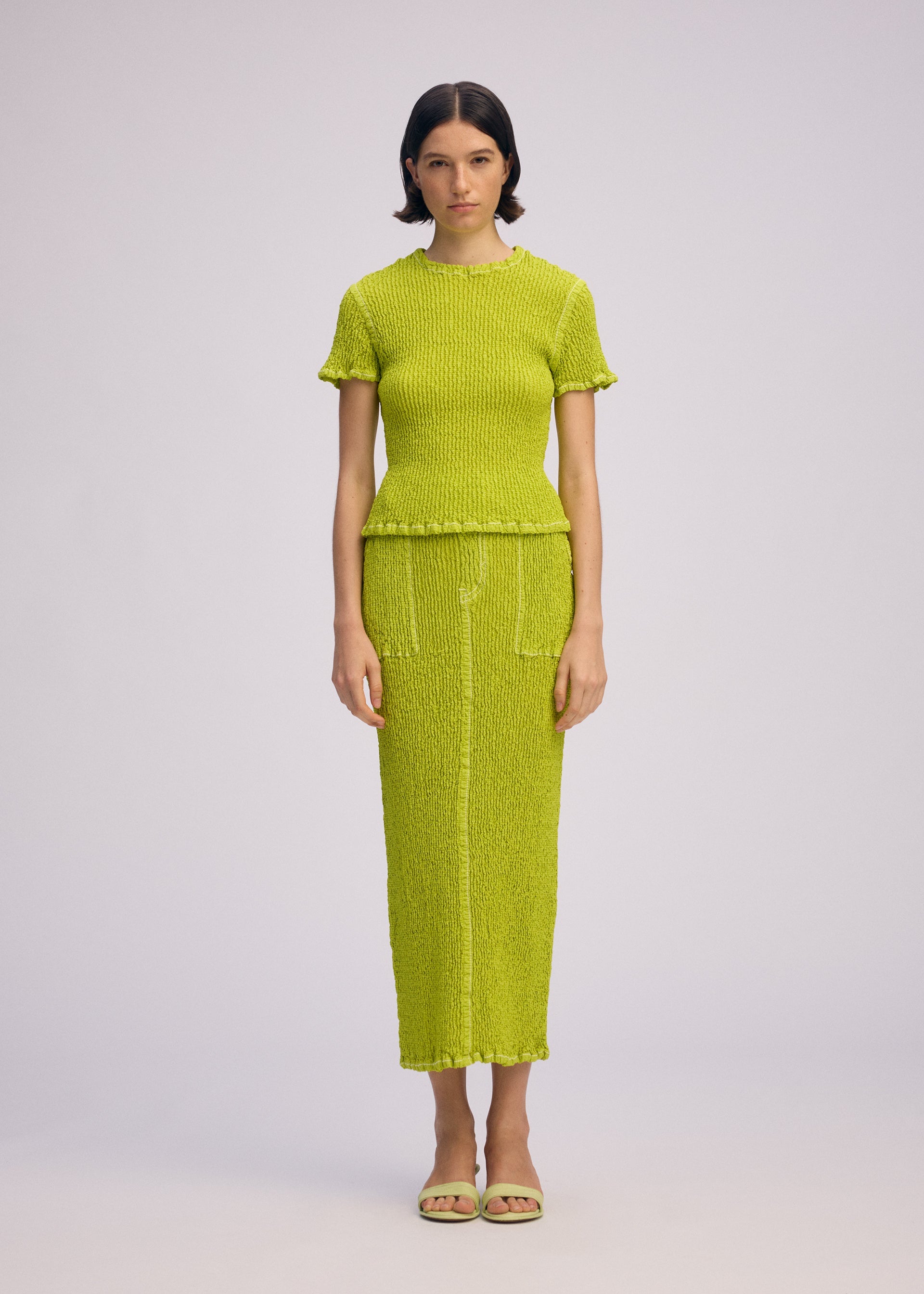 A model wears the ISSEY MIYAKE WAVELET ENSEMBLE skirt.