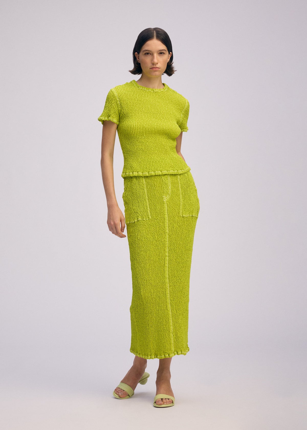 A model wears the ISSEY MIYAKE WAVELET ENSEMBLE skirt.