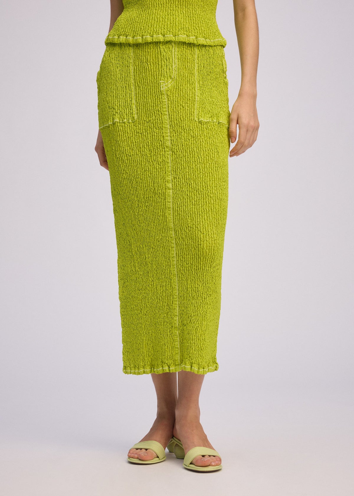 A model wears the ISSEY MIYAKE WAVELET ENSEMBLE skirt.