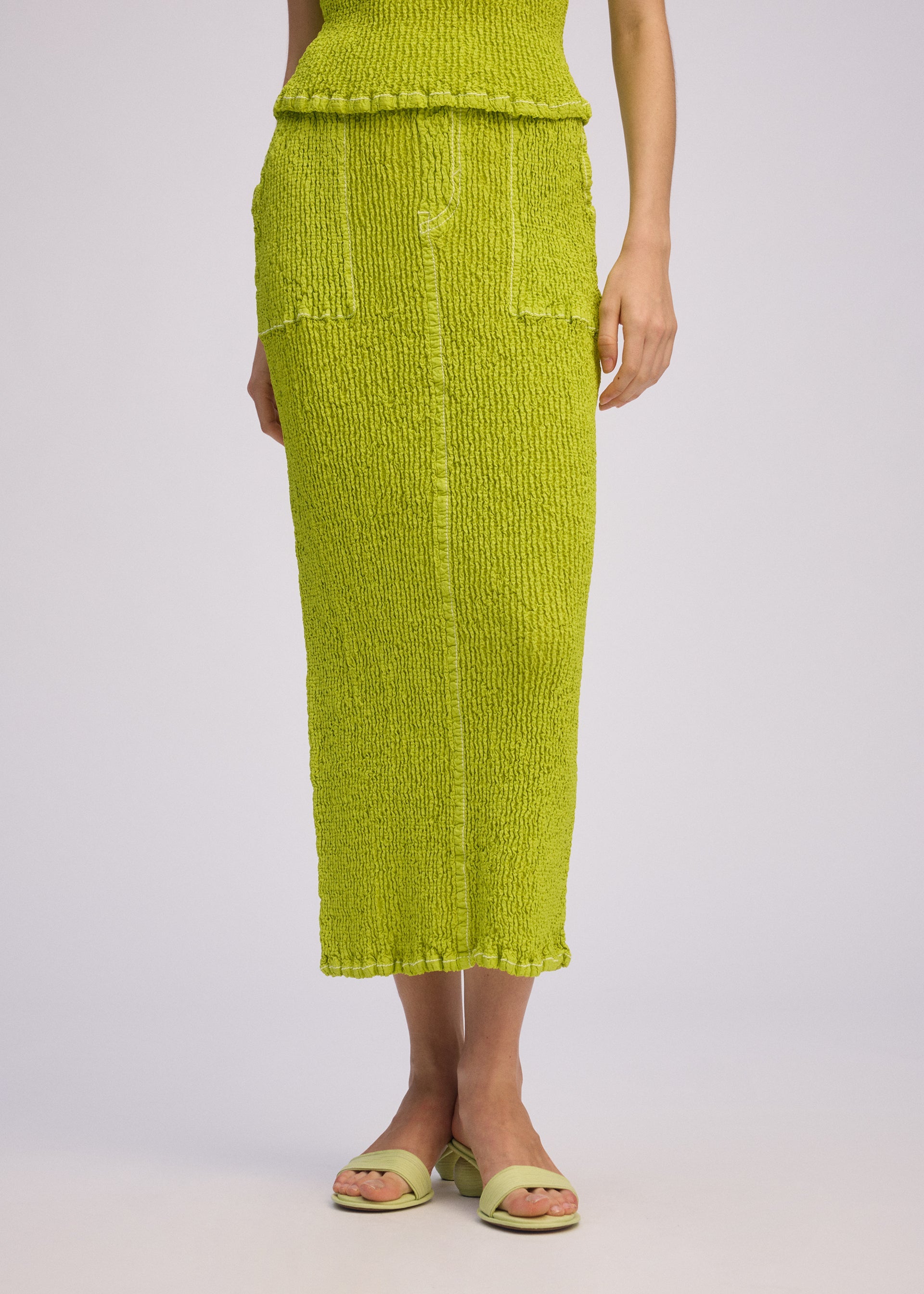 A model wears the ISSEY MIYAKE WAVELET ENSEMBLE skirt.