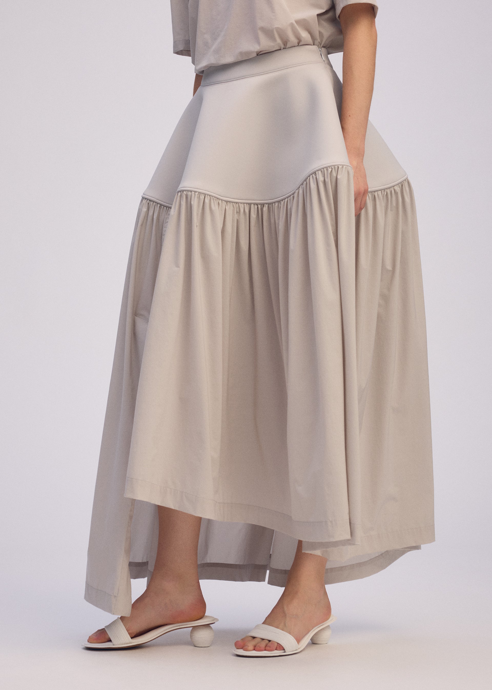 A model wears the ISSEY MIYAKE MUTE mute-skirt-light-grey.