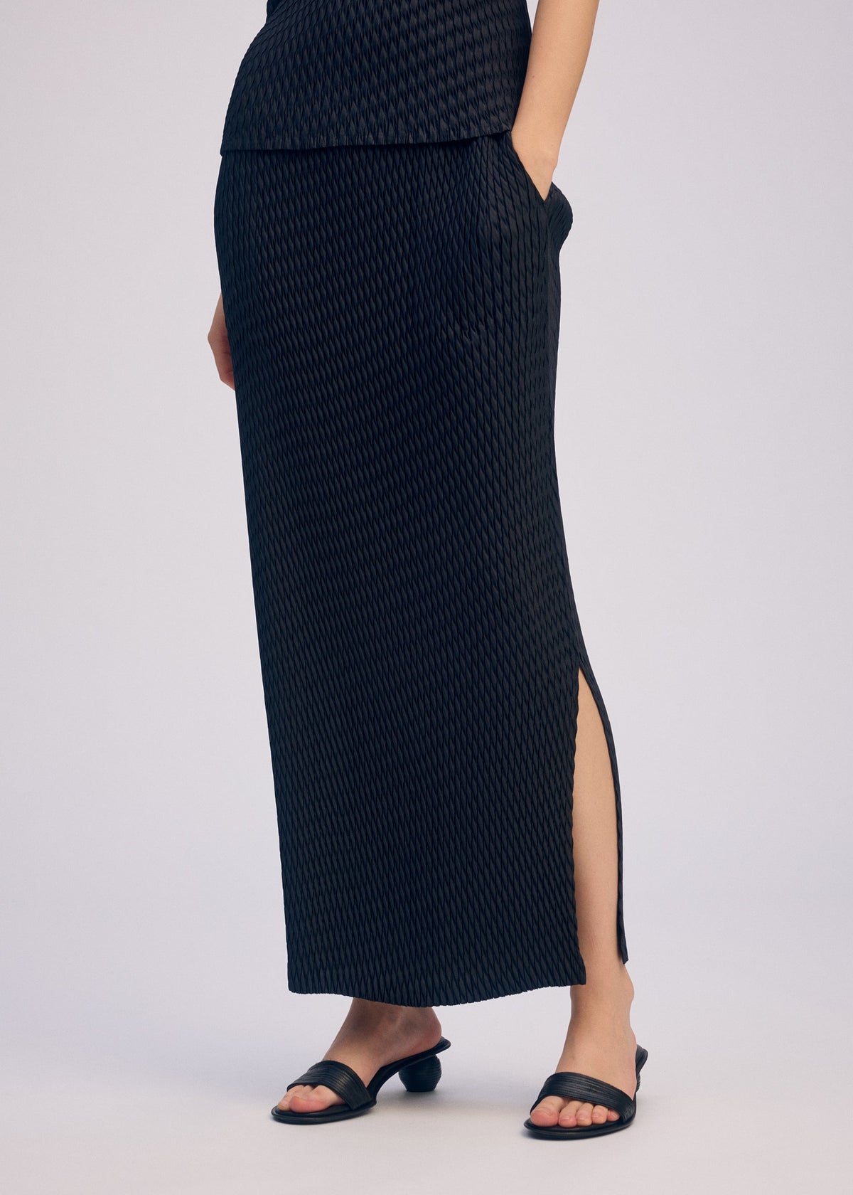 A model wears the ISSEY MIYAKE SLEEK PLEATS sleek-pleats-skirt-light-grey-1.