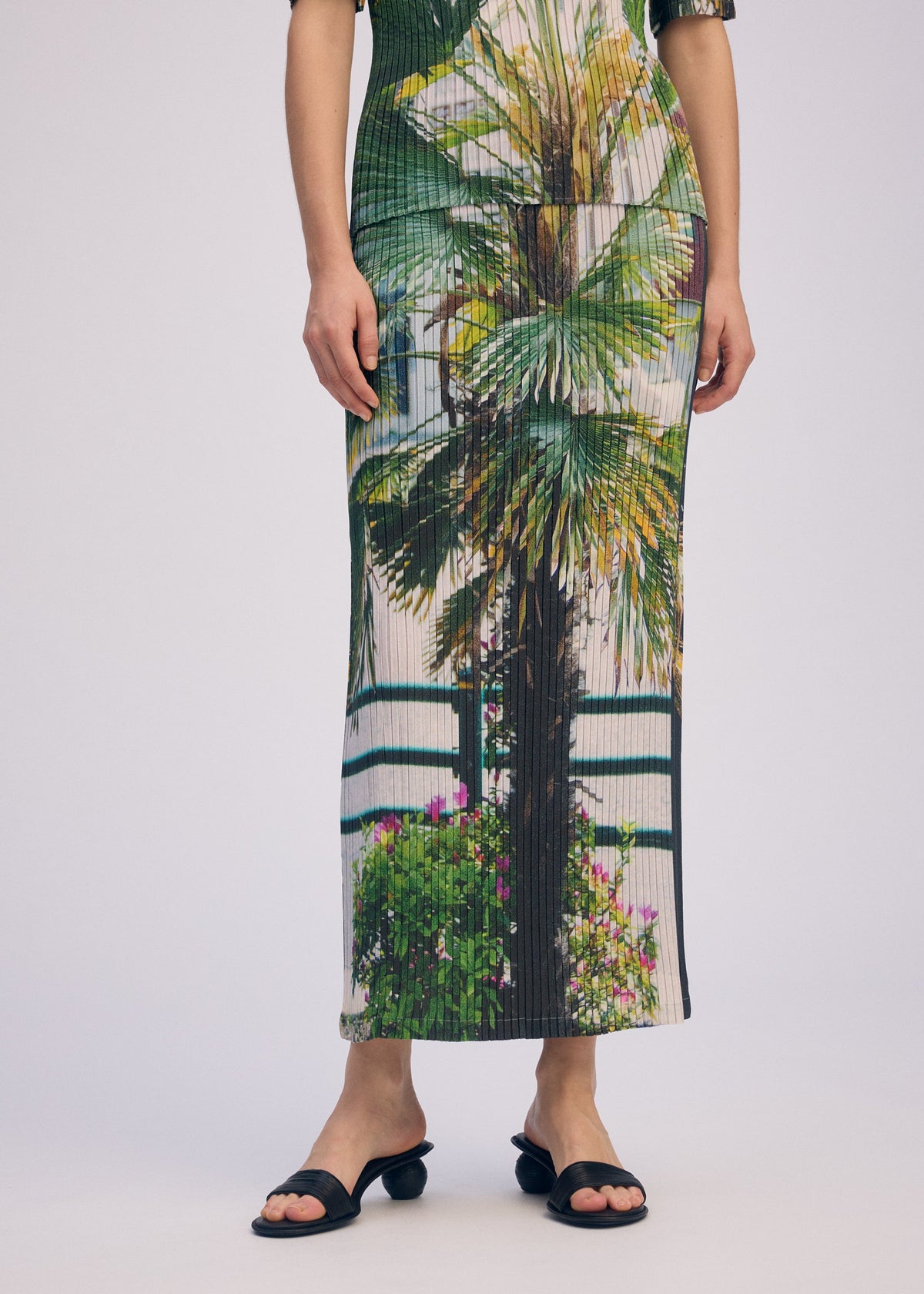 A model wears the ISSEY MIYAKE URBAN JUNGLE PLEATS skirt.