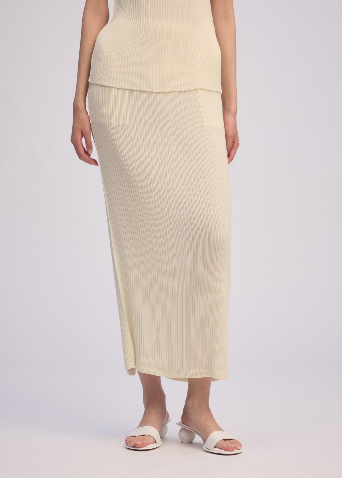 A model wears the ISSEY MIYAKE HATCHING PLEATS skirt.