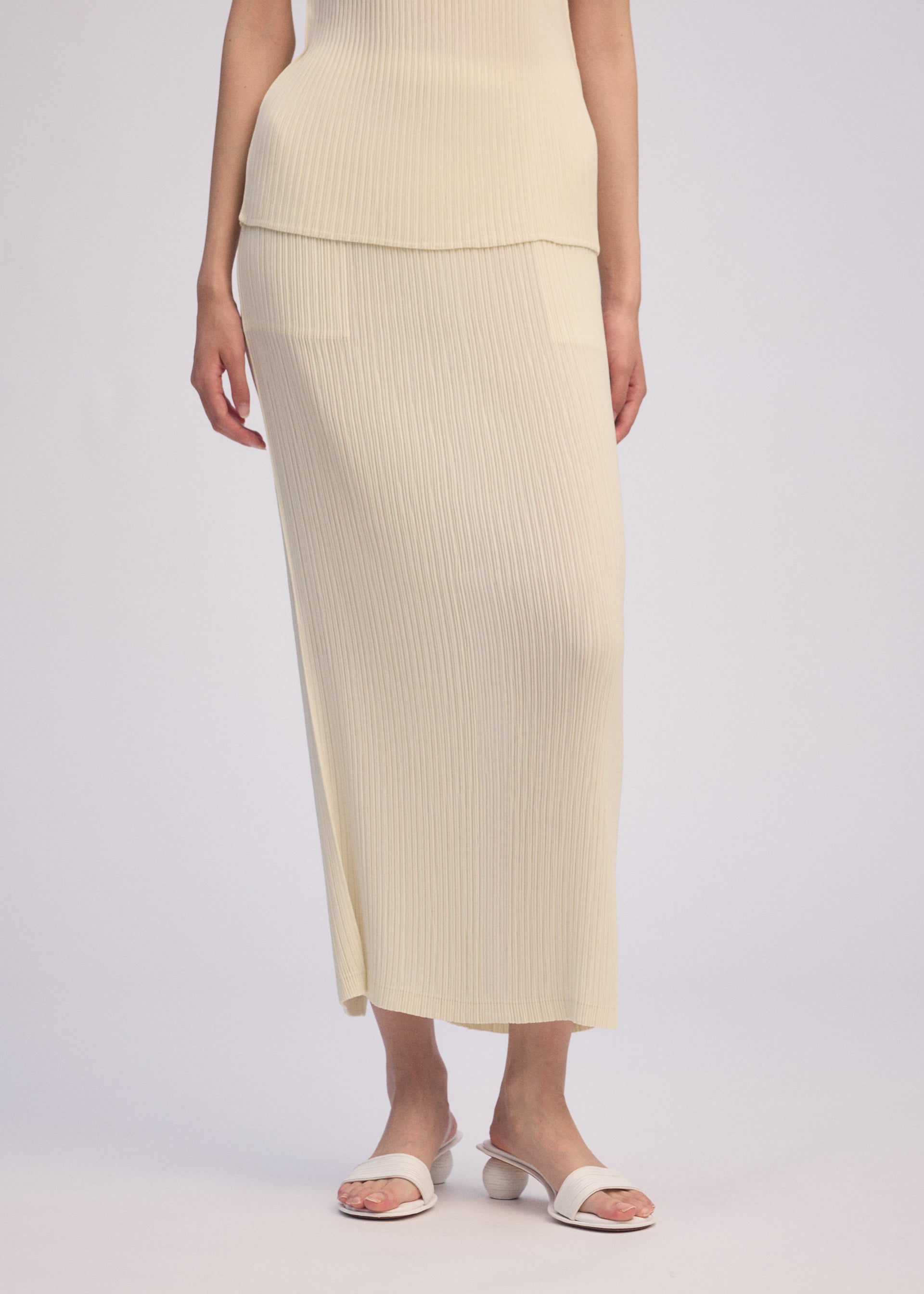 A model wears the ISSEY MIYAKE HATCHING PLEATS skirt.