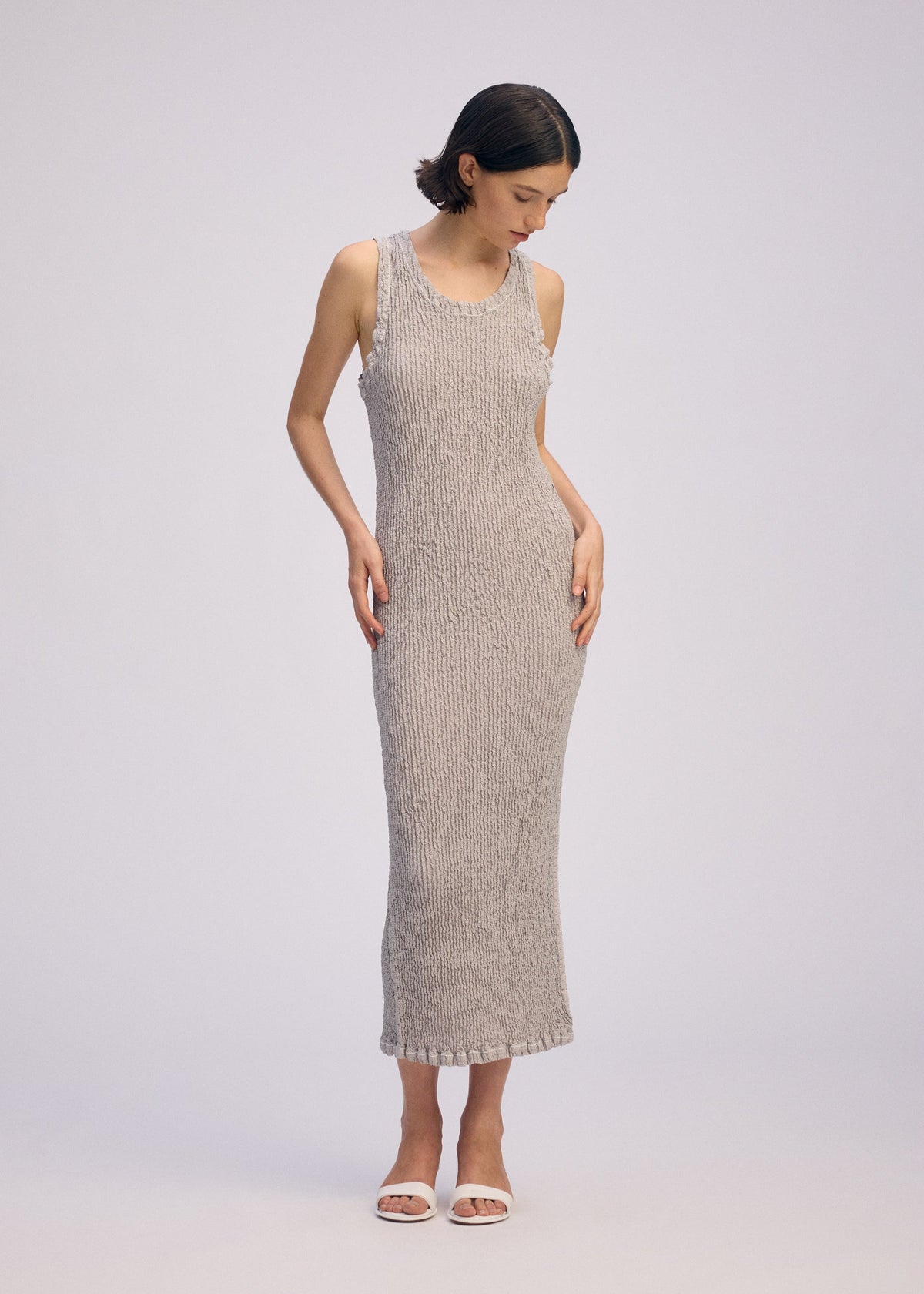 A model wears the ISSEY MIYAKE WAVELET ENSEMBLE dress.