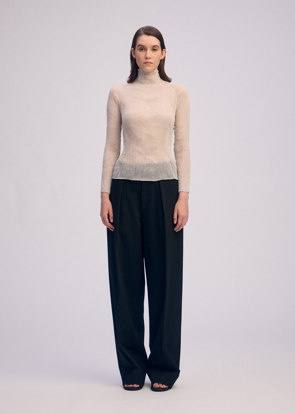 A model wears the ISSEY MIYAKE CHIFFON TWIST 3 top.