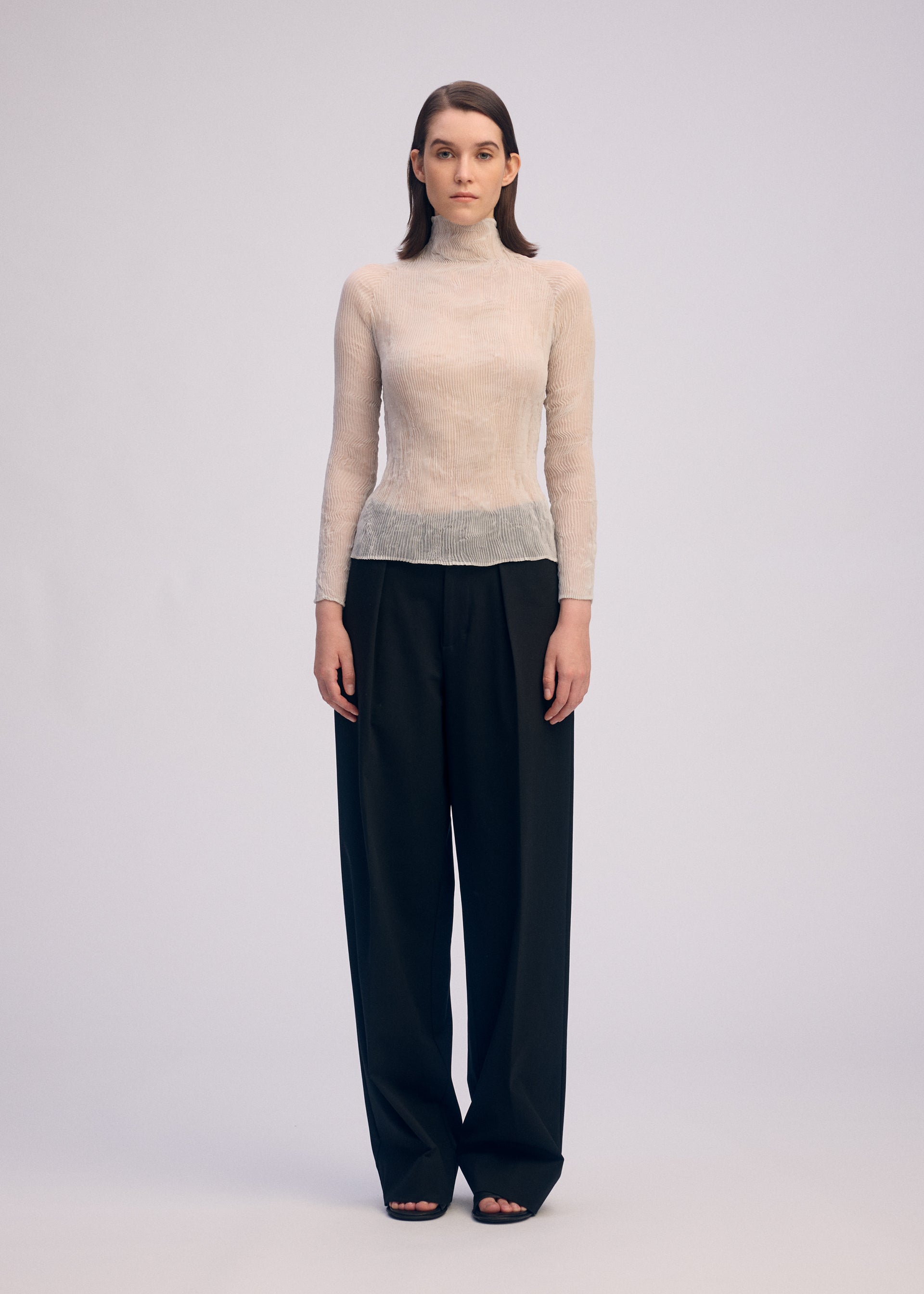 A model wears the ISSEY MIYAKE CHIFFON TWIST 3 top.
