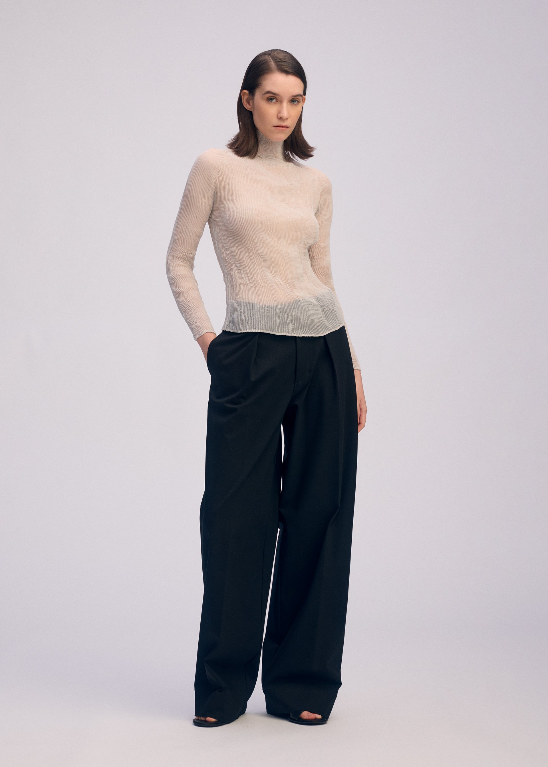 A model wears the ISSEY MIYAKE CHIFFON TWIST 3 top.