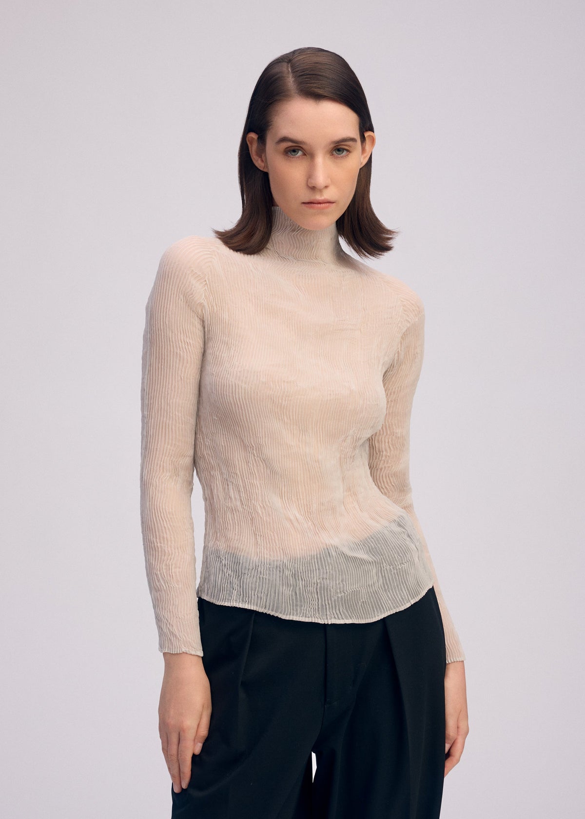 A model wears the ISSEY MIYAKE CHIFFON TWIST 3 top.
