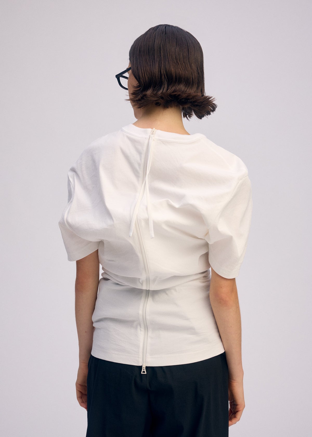 A model wears the ISSEY MIYAKE GENERIC WEAR shirt.