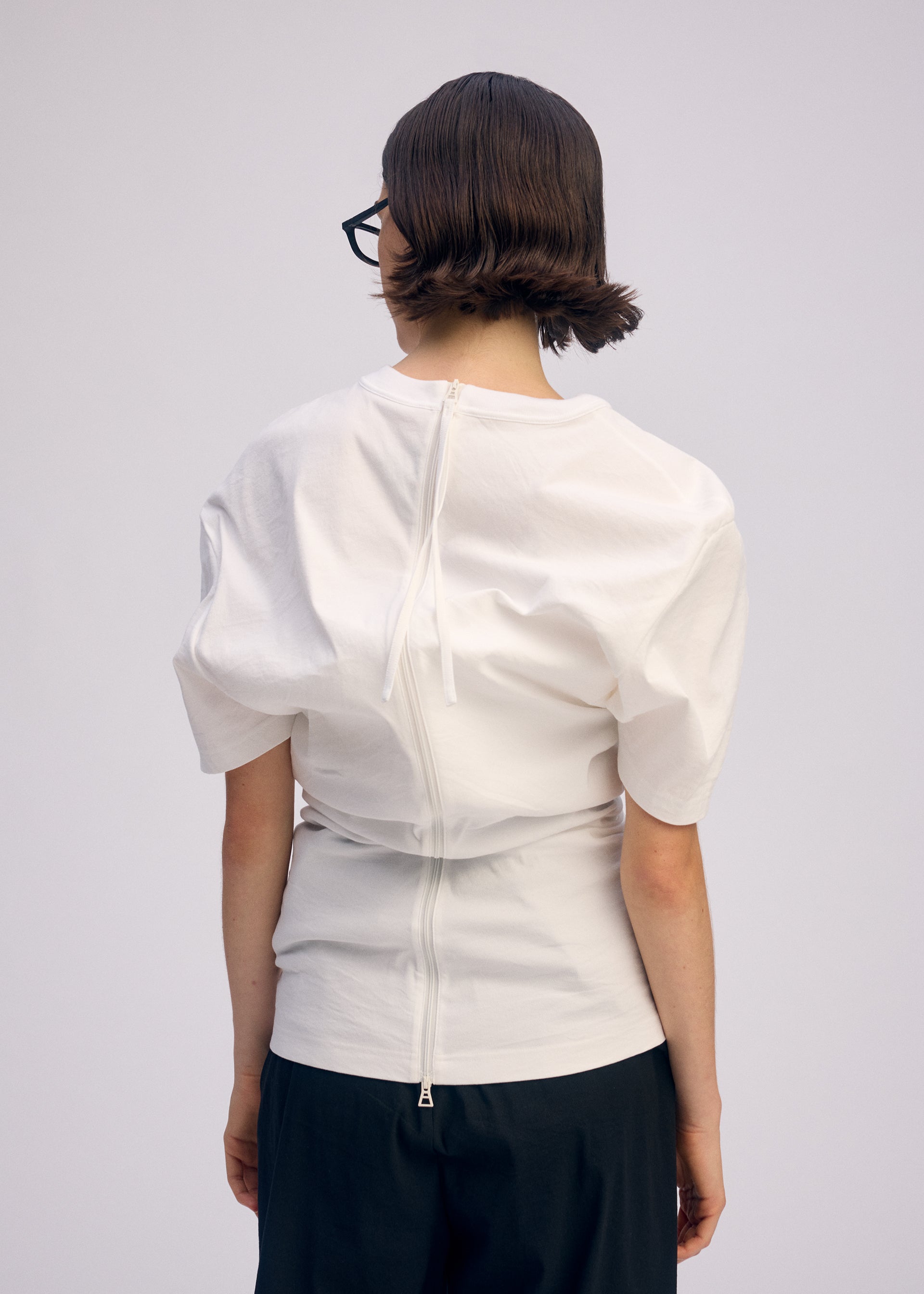A model wears the ISSEY MIYAKE GENERIC WEAR shirt.