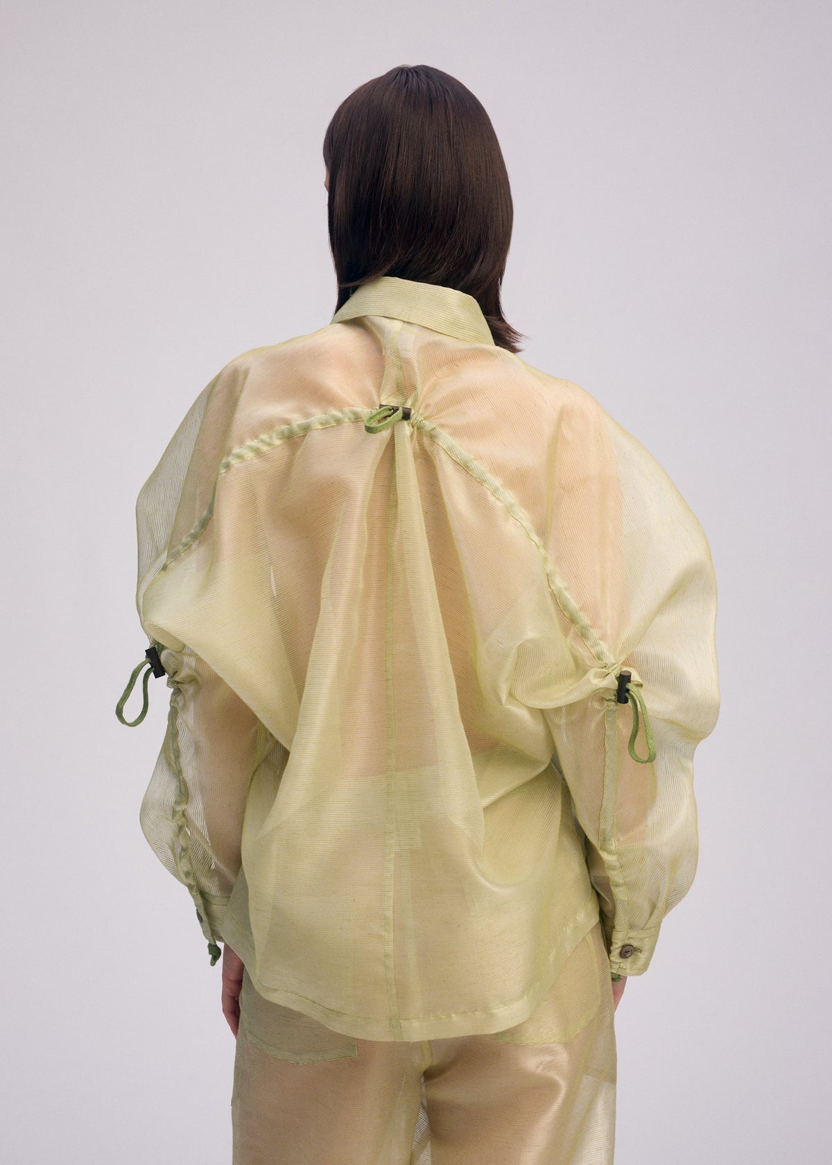 A model wears the ISSEY MIYAKE DRAW TO FORM shirt.