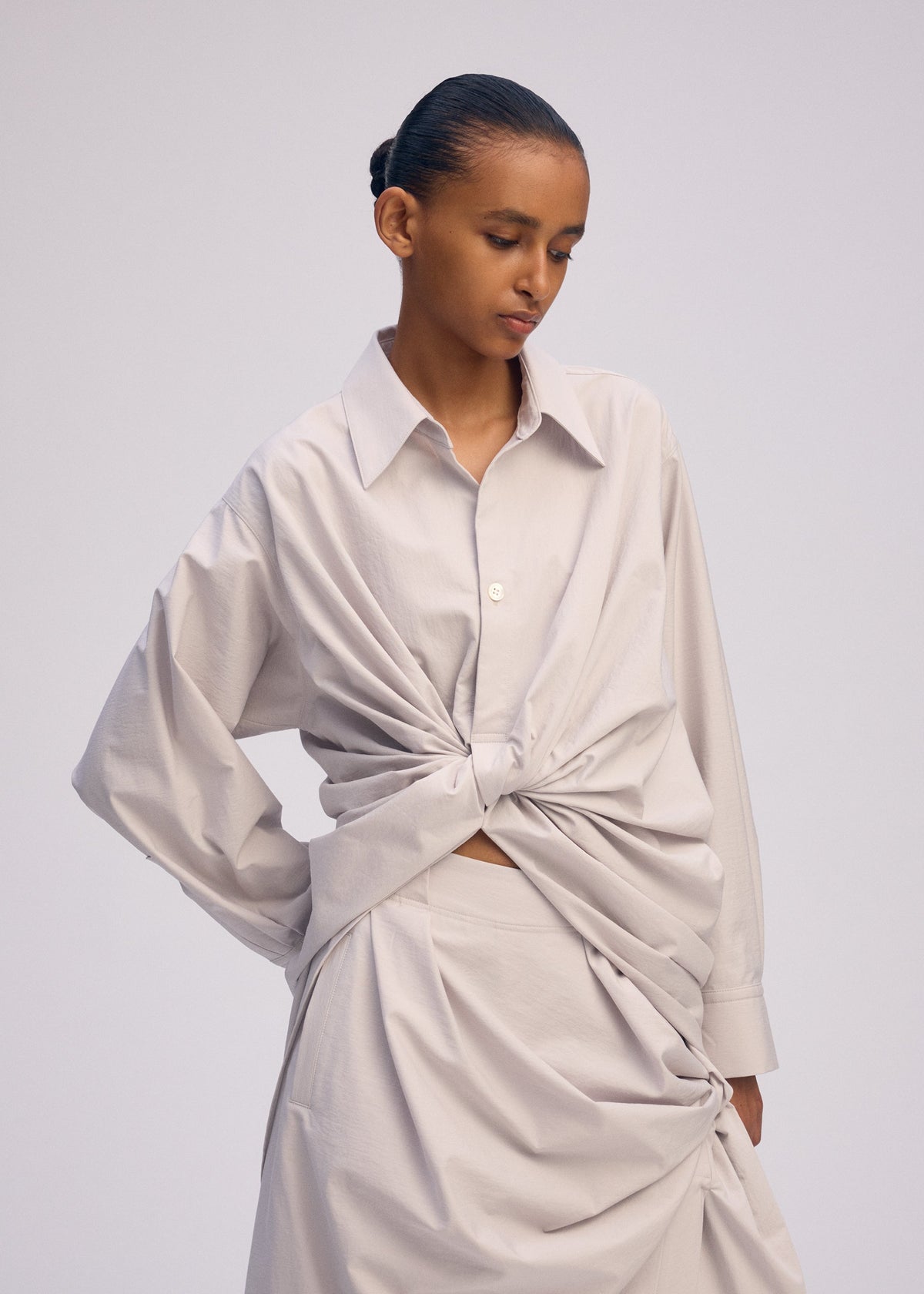 A model wears the ISSEY MIYAKE TWISTED DRAPE shirt.