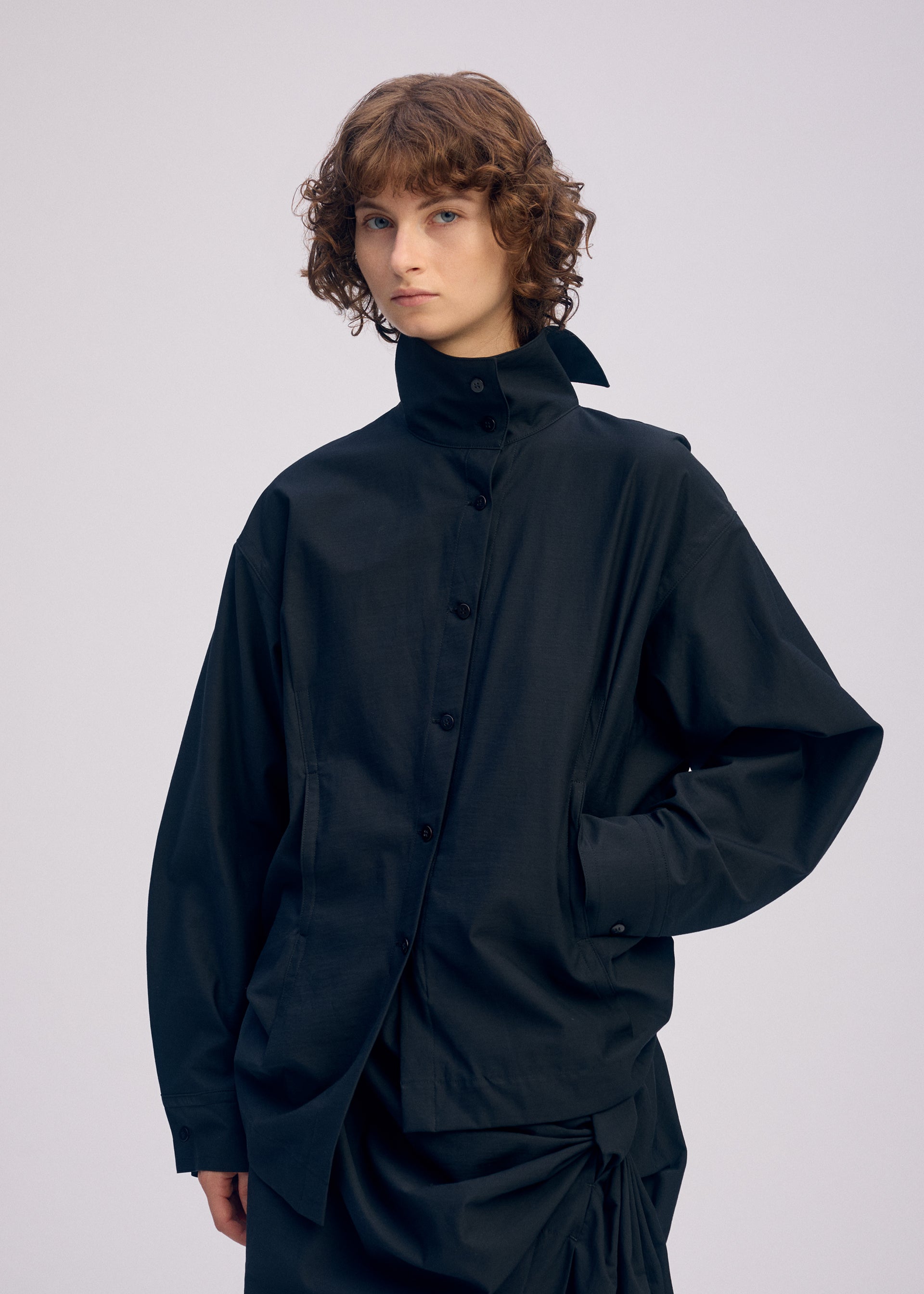 A model wears the ISSEY MIYAKE TWISTED DRAPE shirt.
