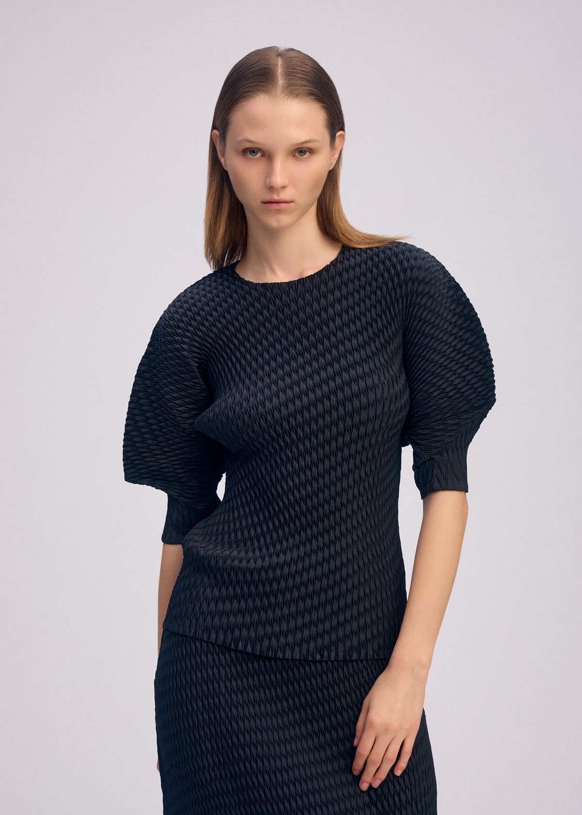 A model wears the ISSEY MIYAKE SLEEK PLEATS sleek-pleats-shirt-burgundy.