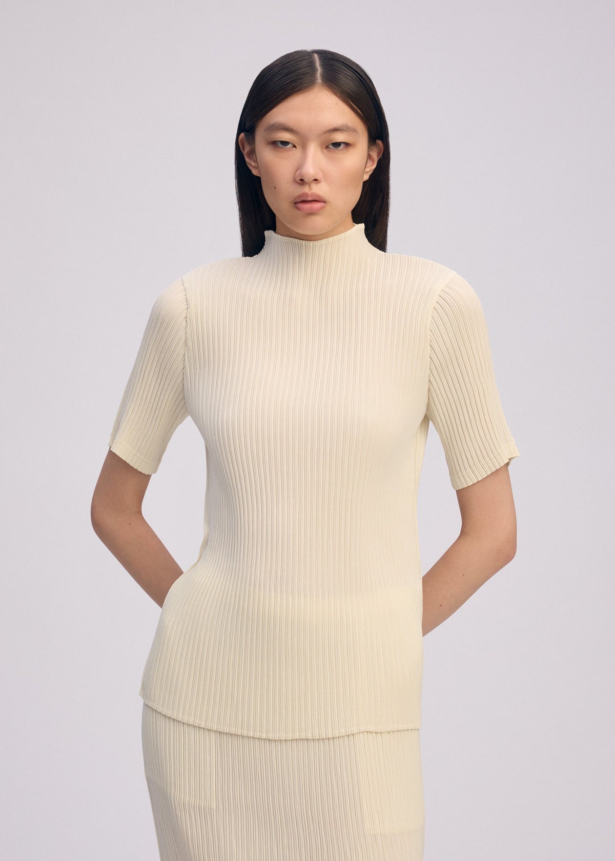 A model wears the ISSEY MIYAKE HATCHING PLEATS shirt.
