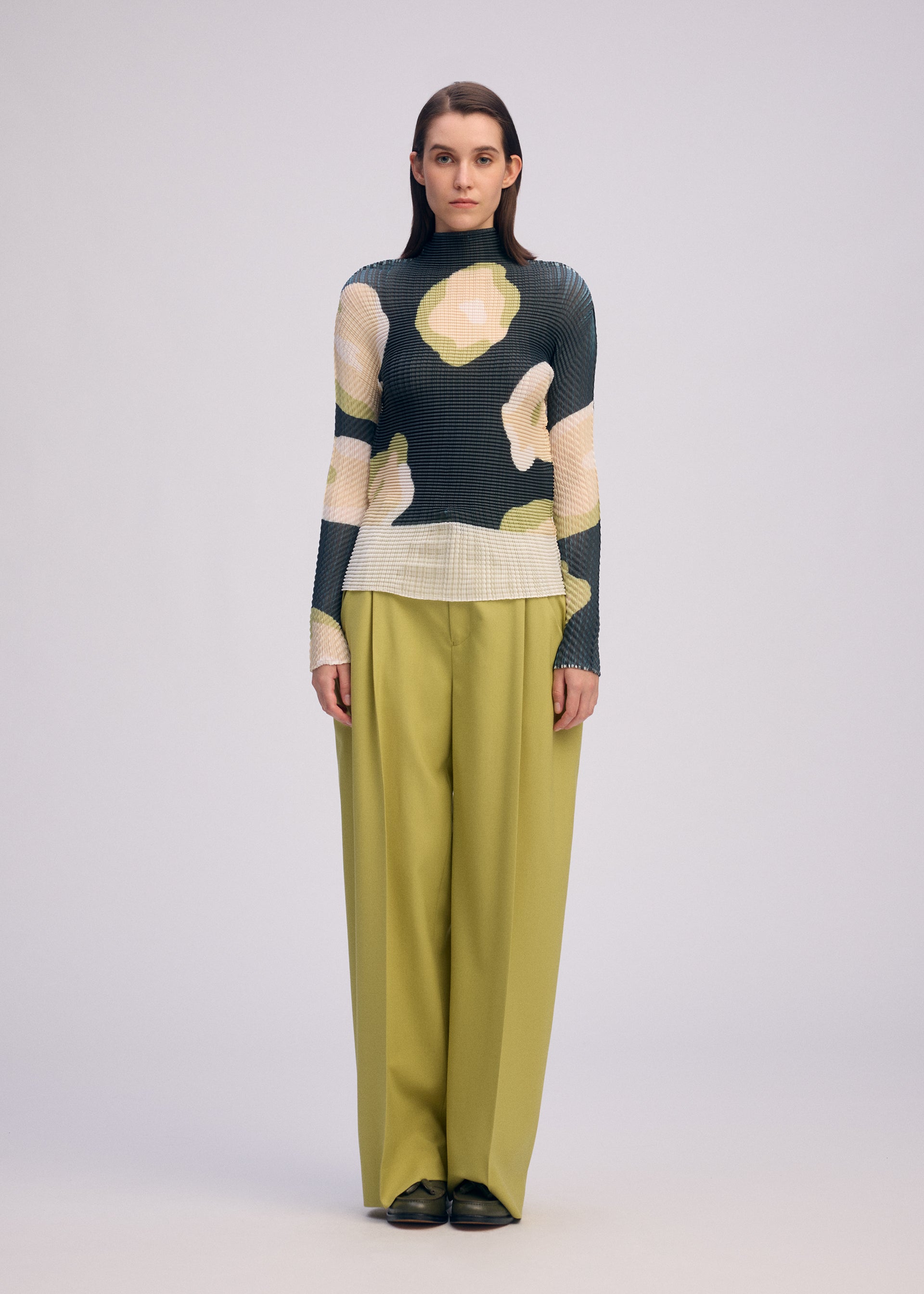 A model wears the ISSEY MIYAKE VERVE PLEATS TOP shirt.